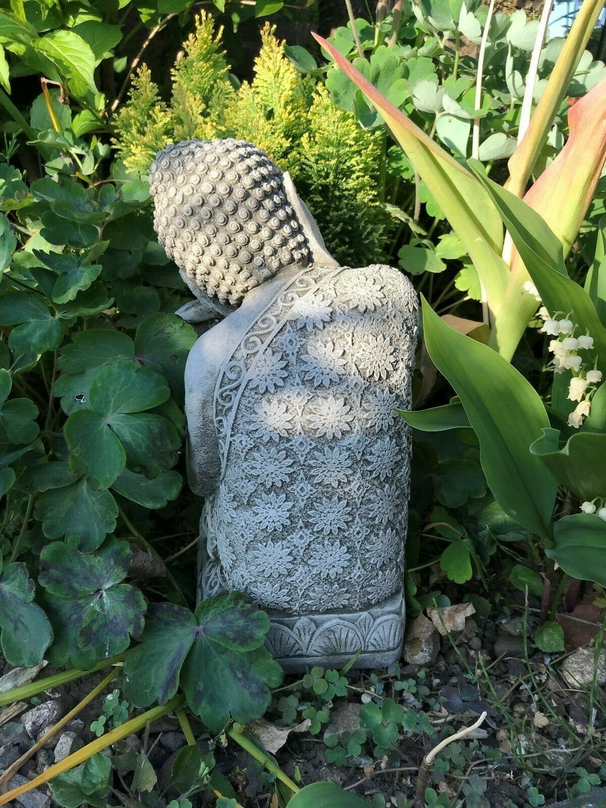Back view of intricately carved Sleeping Buddha garden statue in stone, showcasing floral patterns and serene craftsmanship for outdoor decor.