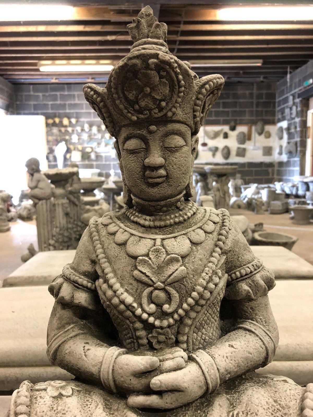 Serene Buddha Statue Garden - Meditating Stone | Peaceful Decor. Close-up of meditating Buddha statue with floral and beaded carvings for peaceful home decor.