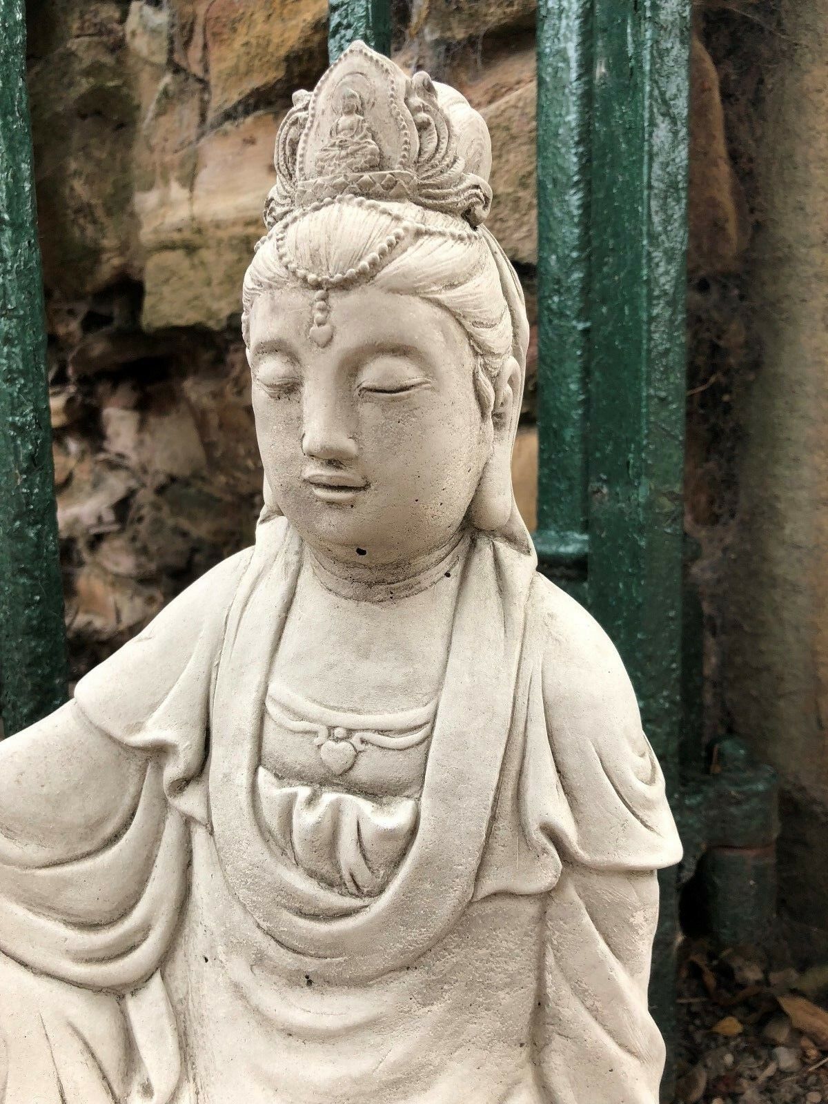 Close-up of Kuan Yin statue's face and crown, showing intricate stone carving. Durable 18" garden sculpture for peaceful outdoor settings.