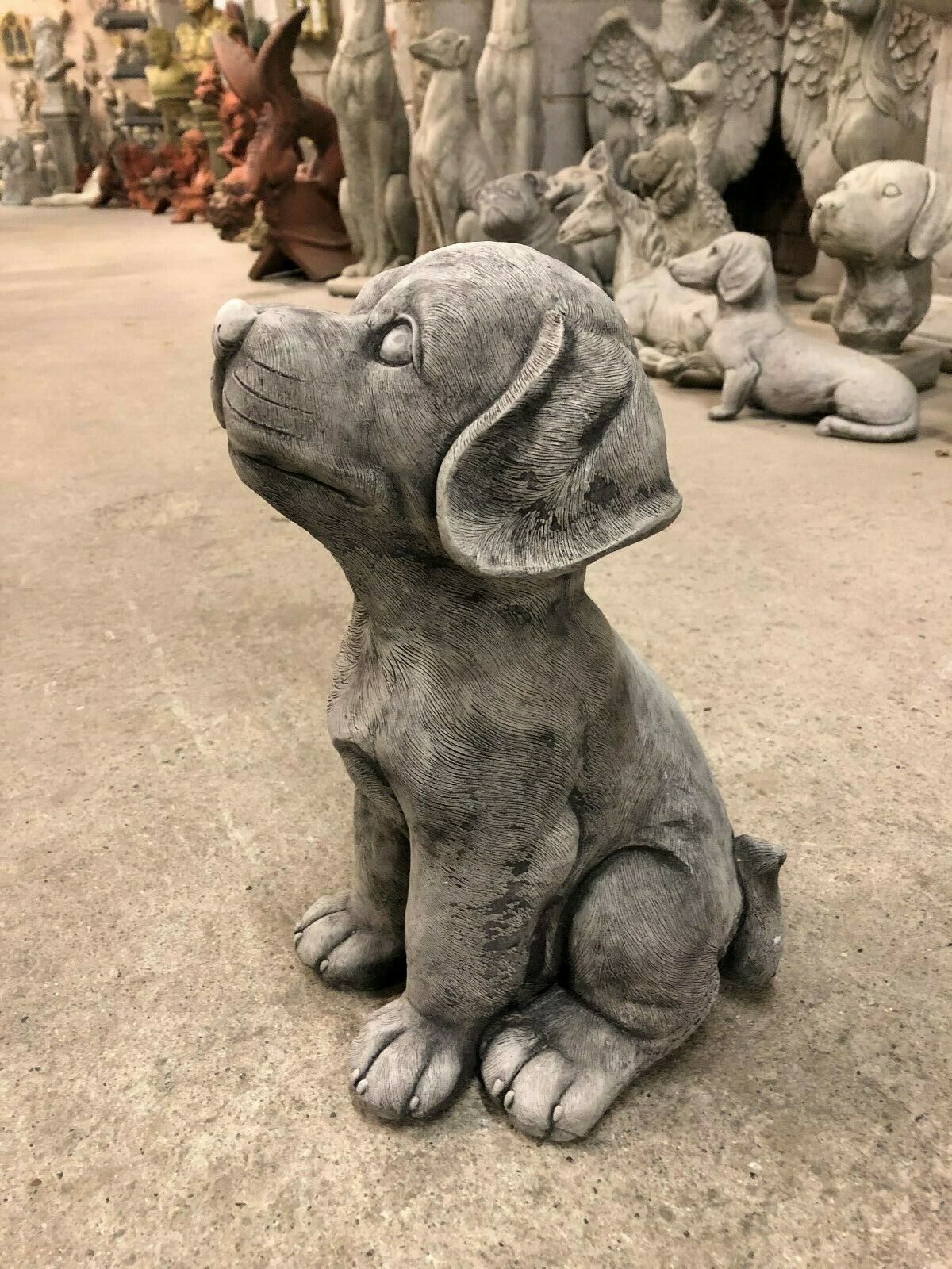 Side profile of stone puppy garden ornament showing realistic ear and paw details. Weather resistant and suitable for outdoor display.