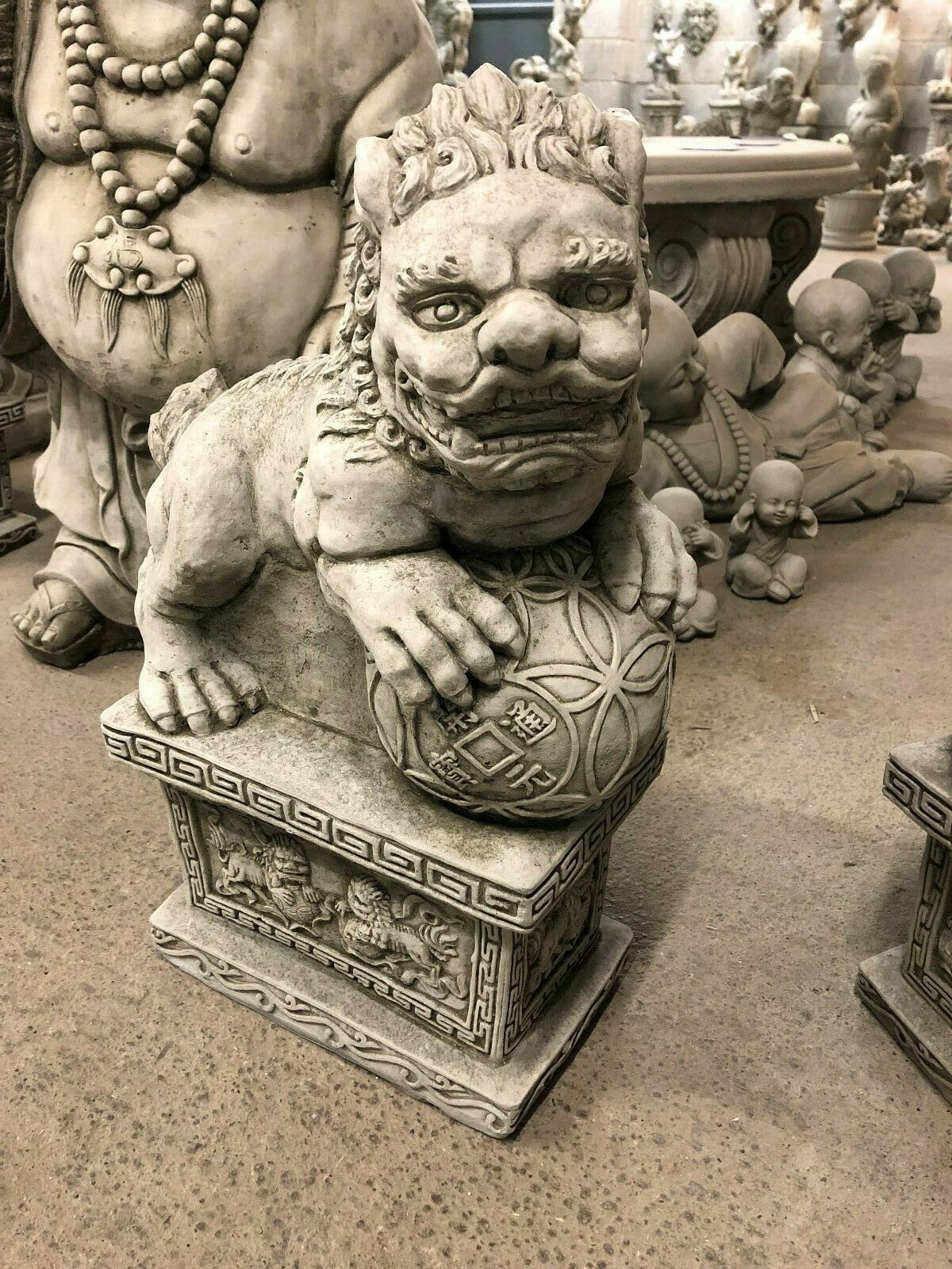 Close-up of a single Foo Dog Statue with paw on a carved ball, showcasing intricate facial features and solid stone craftsmanship.