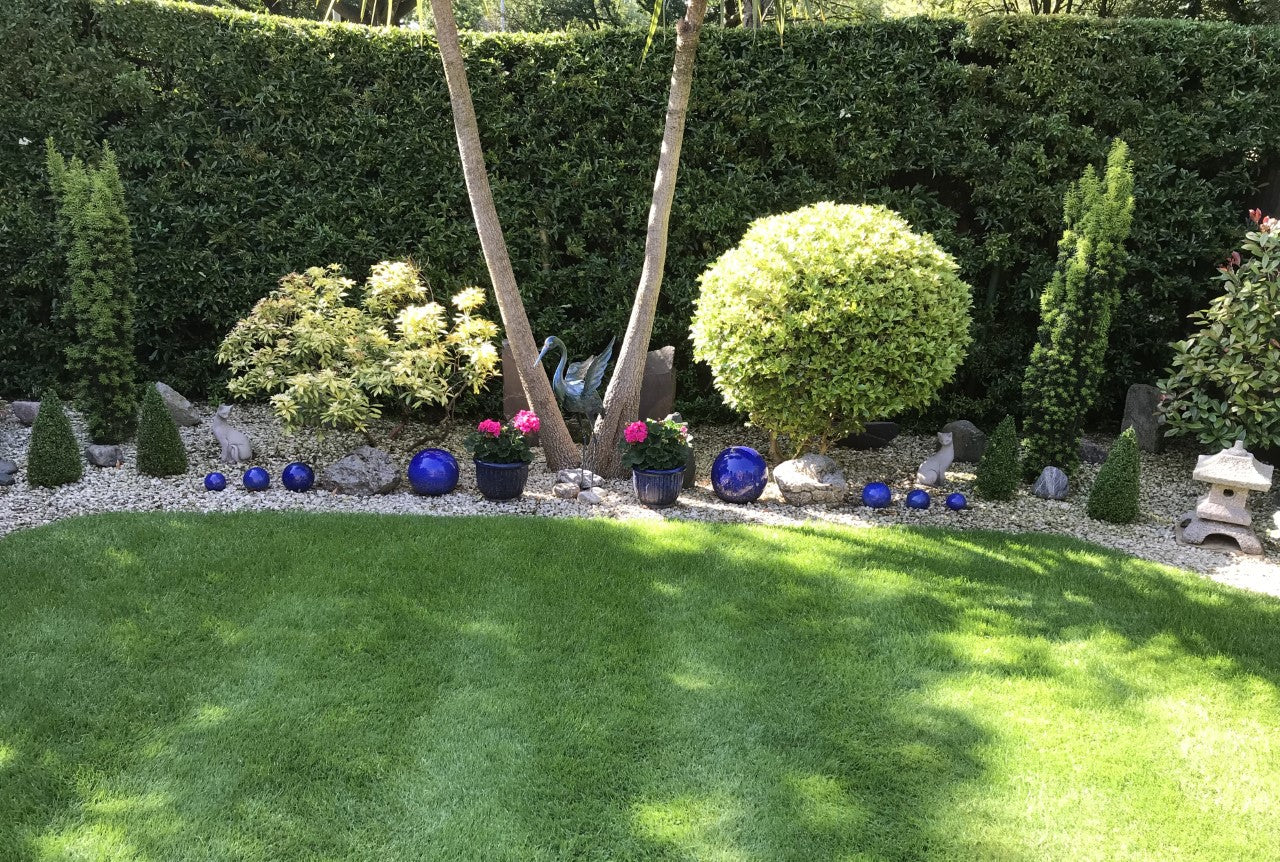 Beautifully landscaped garden with manicured lawn and decorative elements, ideal setting for placing stone Siamese cat statues.
