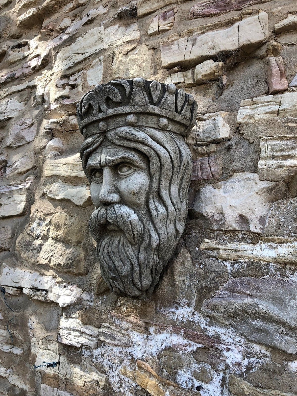 Angled view of Stone Crown Planter mounted on stone wall, highlighting detailed carving and durable outdoor design.