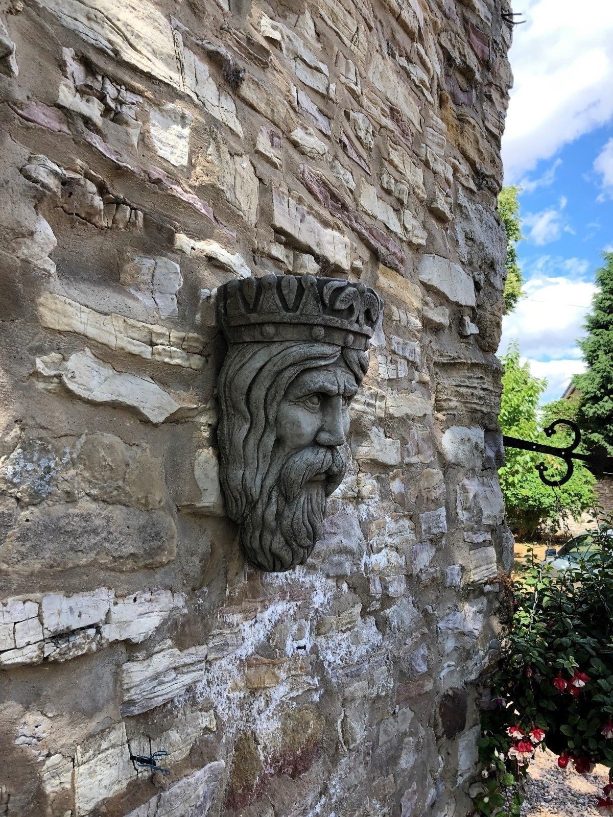 Stone Crown King Garden Planter on exterior wall, surrounded by greenery, ideal for decorative outdoor landscaping.