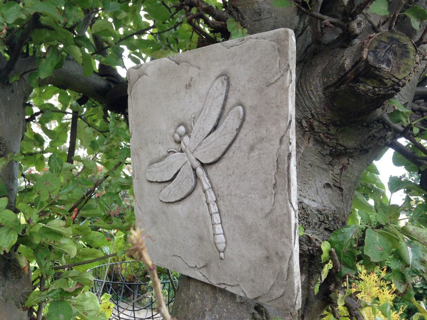 Handmade Dragonfly Wall Plaque in solid limestone. Textured stone square with insect motif, perfect for outdoor garden decoration.