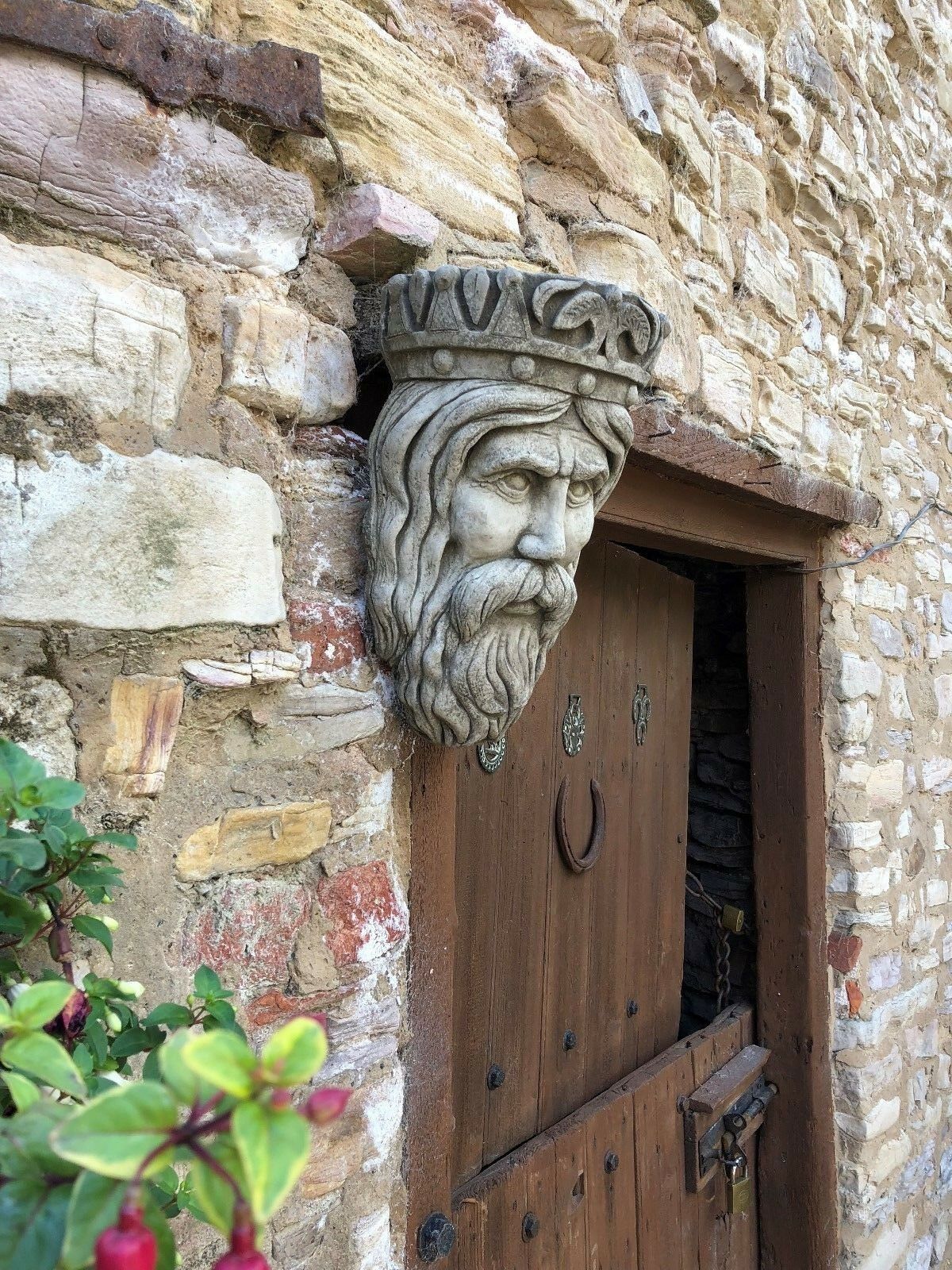 Side profile of Stone Crown Planter above rustic door, emphasizing handcrafted detail and solid limestone structure.