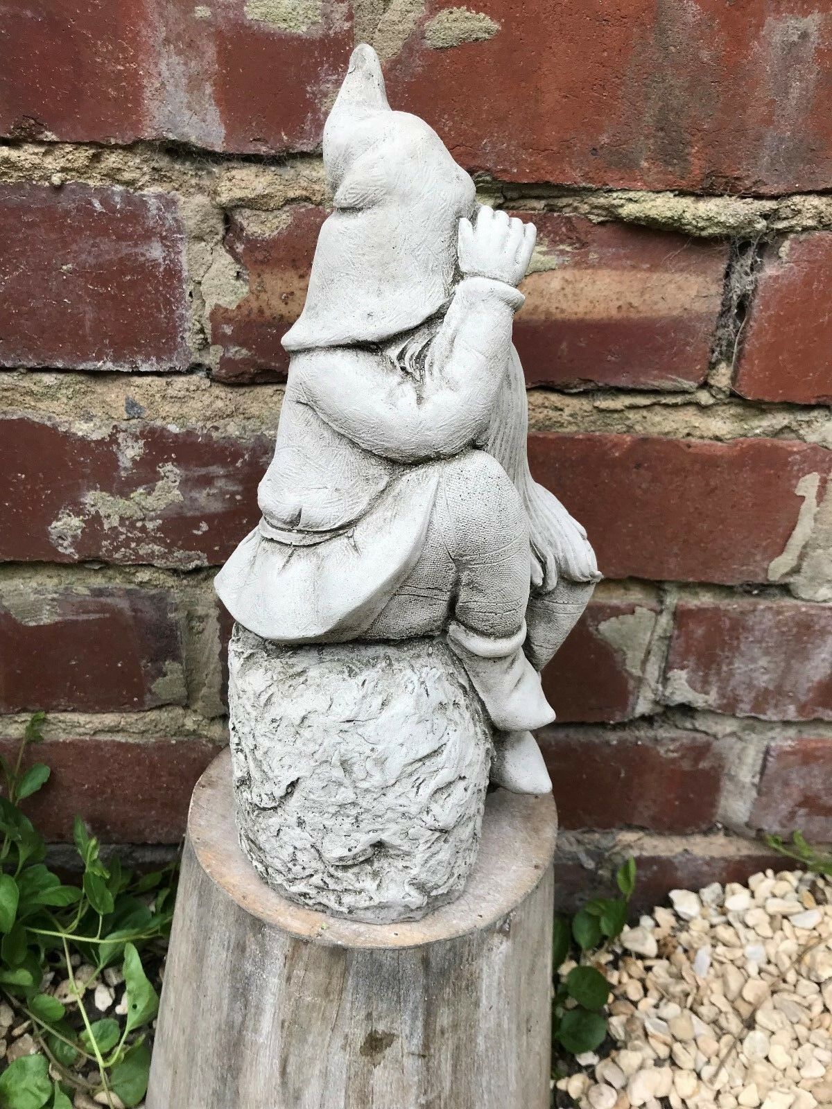 Side view of Stone Searching Garden Gnome Ornament seated on a textured stone base, ideal for patio or garden display.