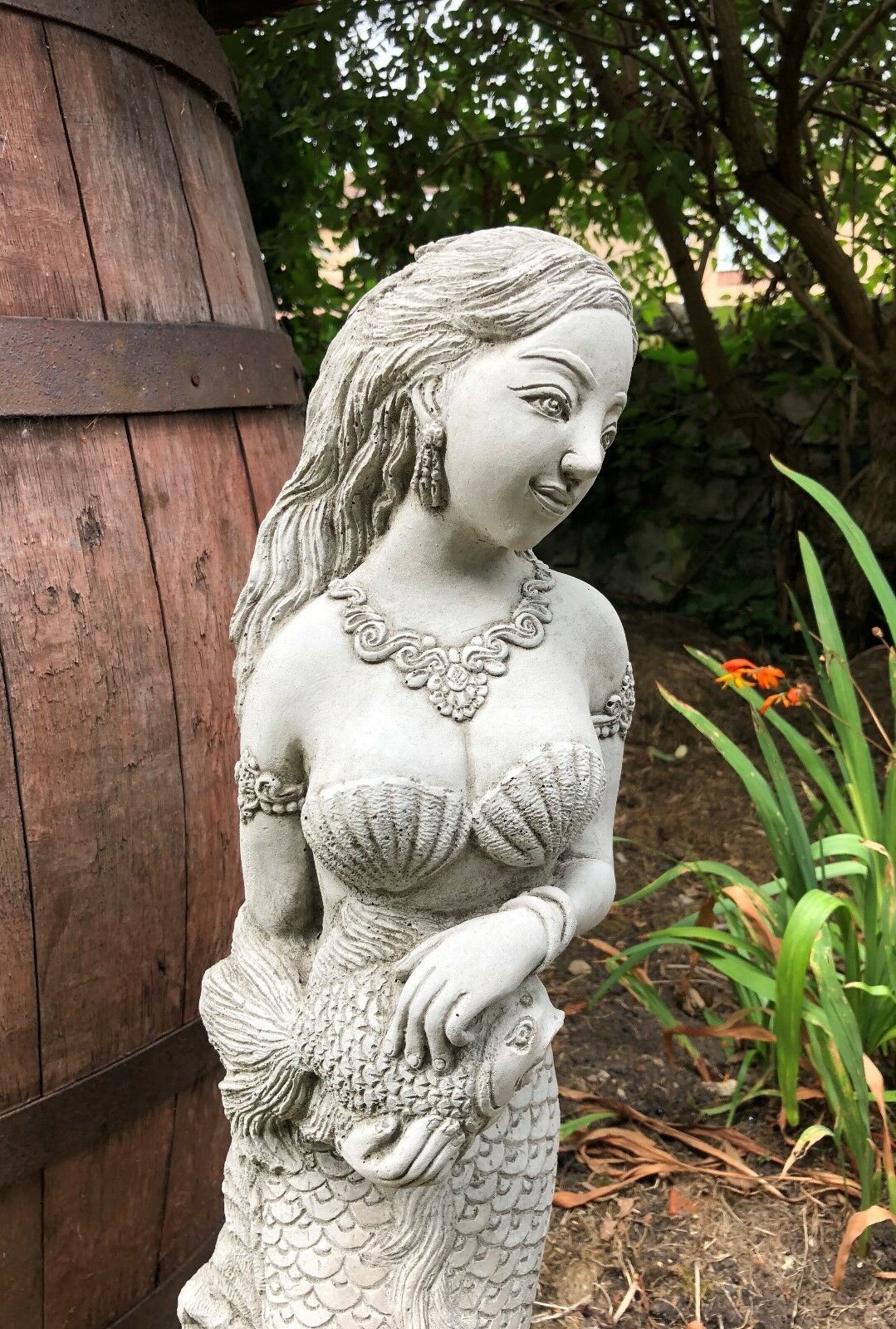 Angled view of Mermaid Garden Ornament with smiling expression and detailed fish spout, enhancing garden water features.