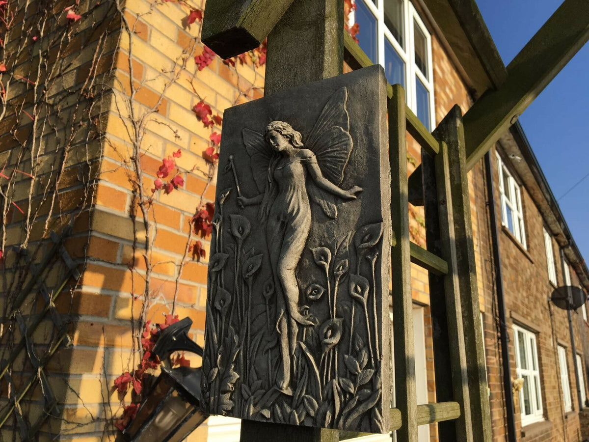 Weather-resistant Fairy Garden Wall Plaque mounted on wooden trellis, showcasing intricate stone fairy design for enchanting garden decoration.