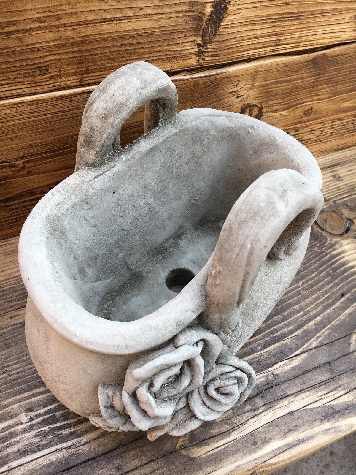 Top view of stone handbag planter with drainage hole and rose embellishment. Perfect for planting flowers in outdoor spaces.