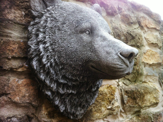Stone Bear Head Wall Ornament mounted on a rustic stone wall, showcasing detailed fur texture and lifelike expression for garden decoration.