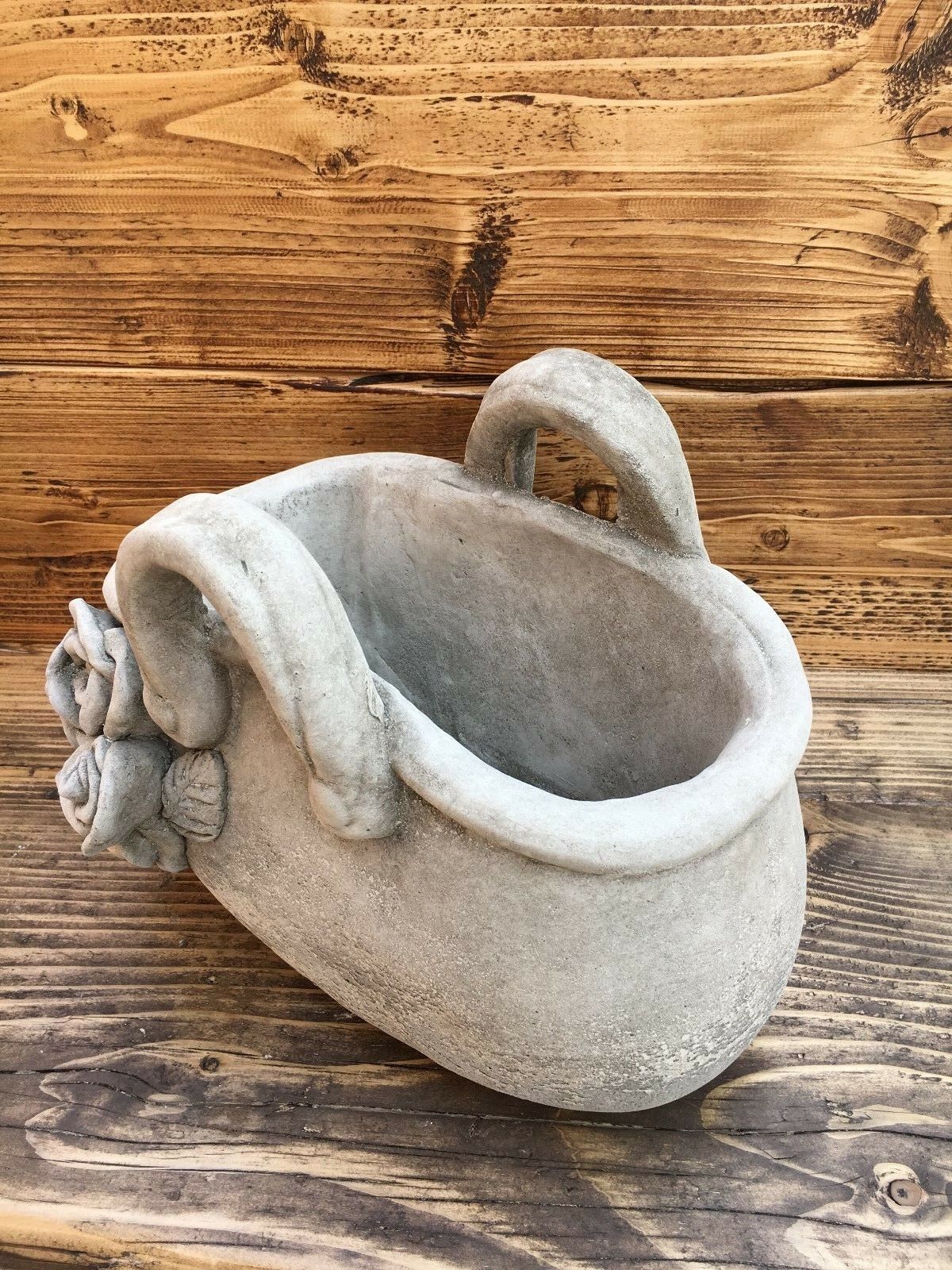 Angled view of stone handbag planter with sculpted rose detail. Elegant and weather-resistant for garden or patio use.