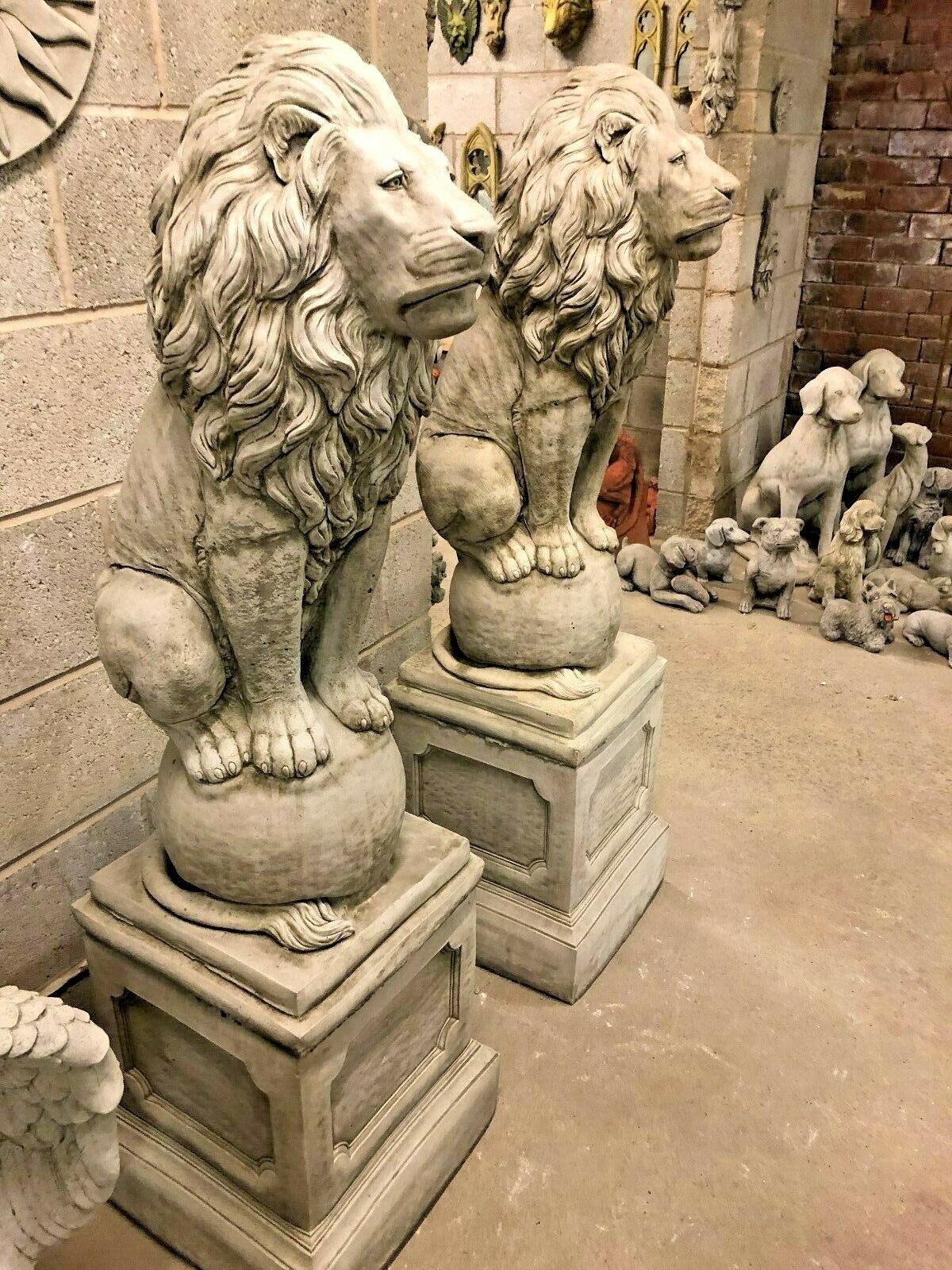 Two majestic stone lion statues on plinths positioned side by side, enhancing the grandeur of any garden or patio setting.
