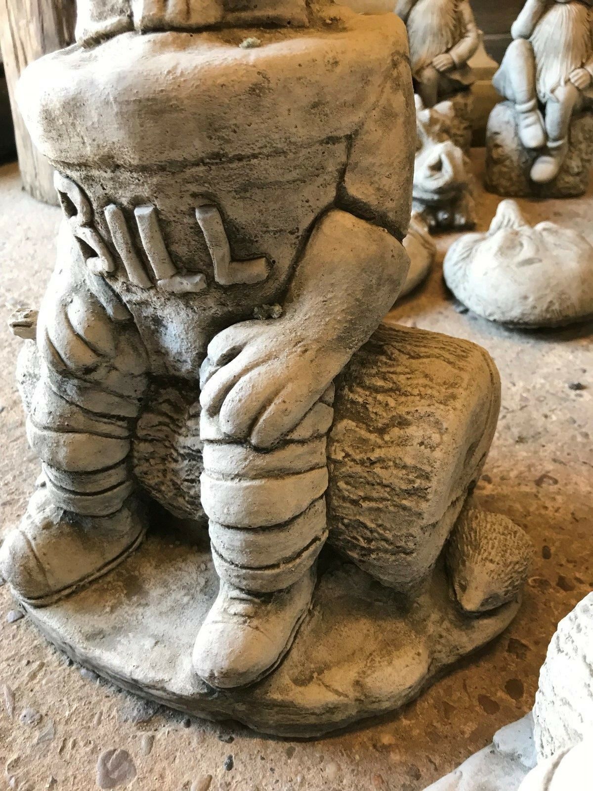 Side view of the Stone Bill statue highlighting the log seat and a hedgehog figure, crafted in durable limestone for outdoor use.