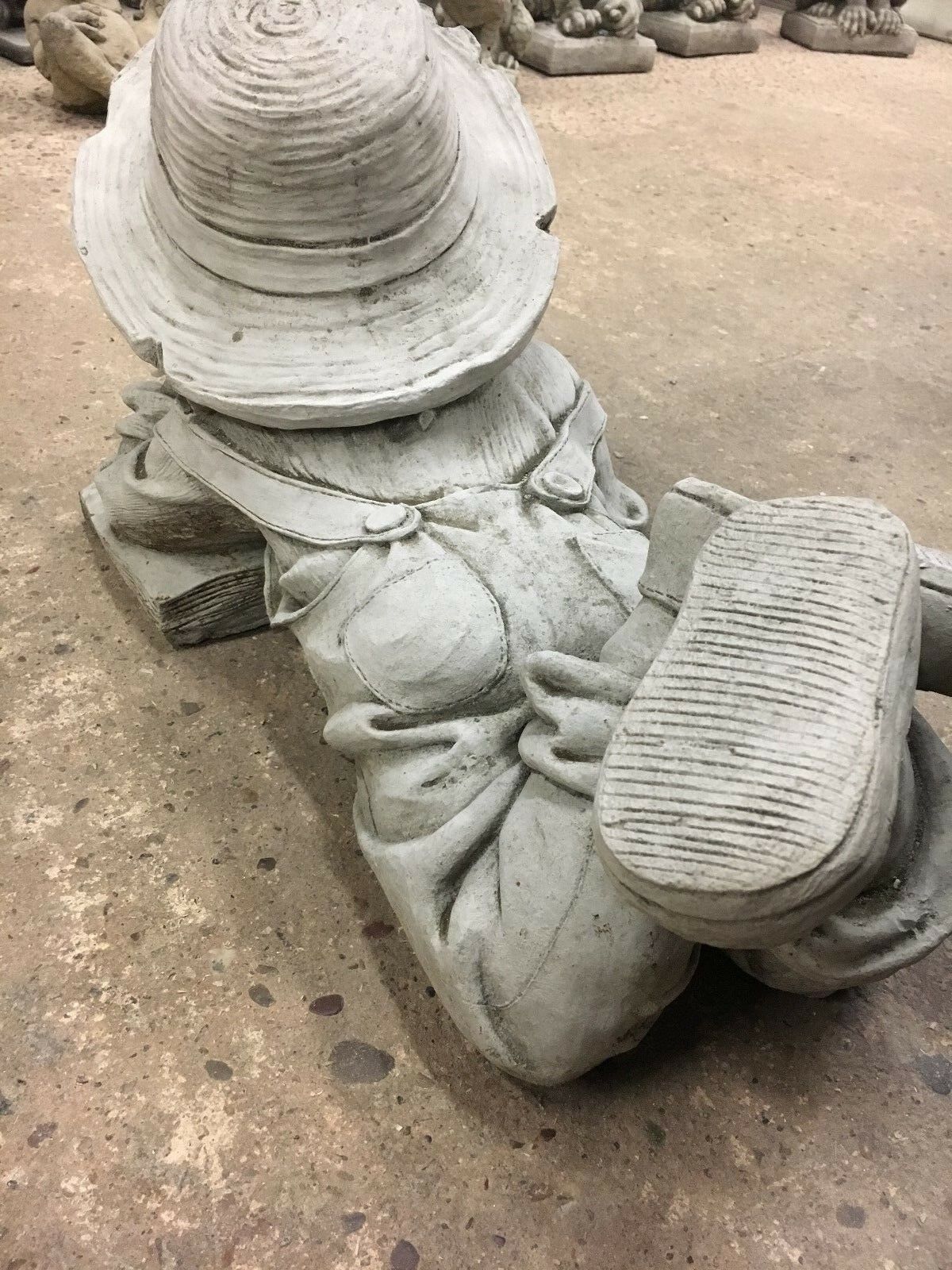 Rear view of Reading Boy Statue in stone finish, highlighting textured boots and sculpted clothing for outdoor garden decor.