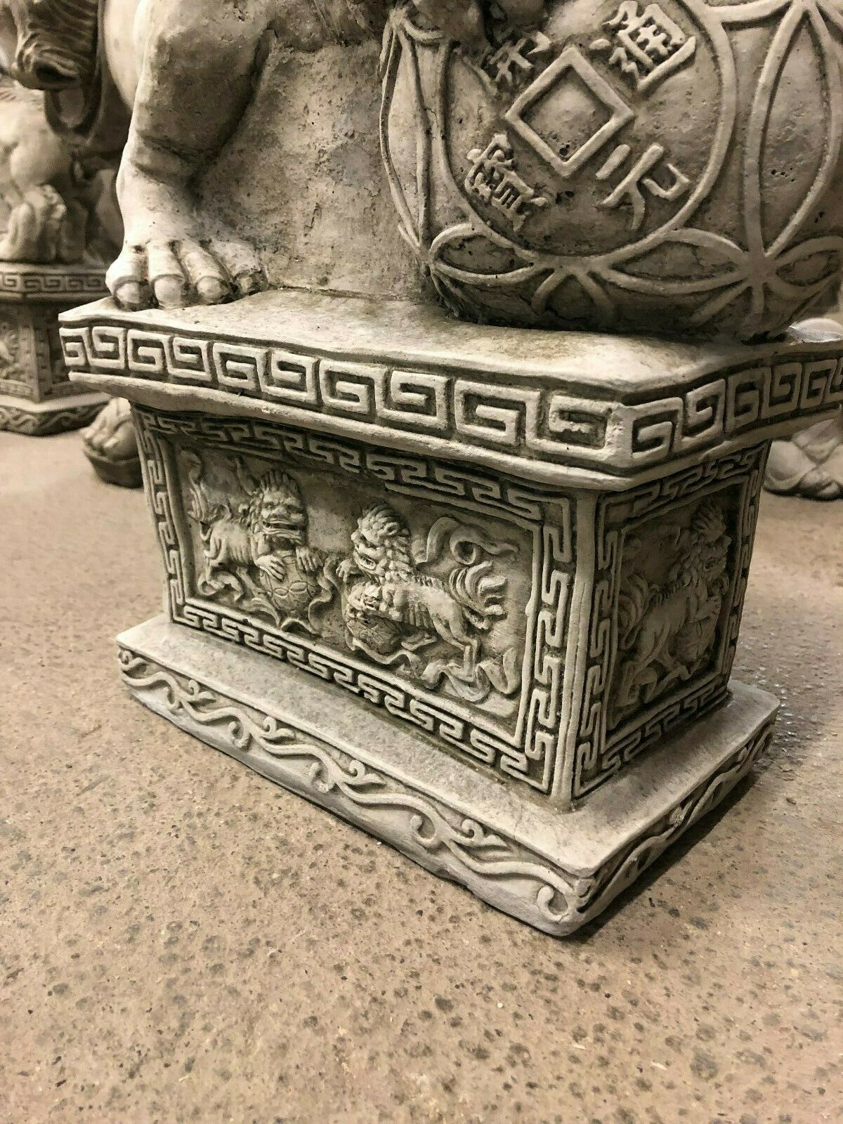 Detailed view of the pedestal base featuring engraved lion motifs and geometric patterns, enhancing the statue's decorative appeal.