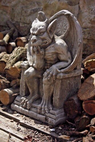 King Gargoyle Stone Statue - Weather Resistant Garden Art placed outdoors among firewood, demonstrating durability and rustic garden appeal.