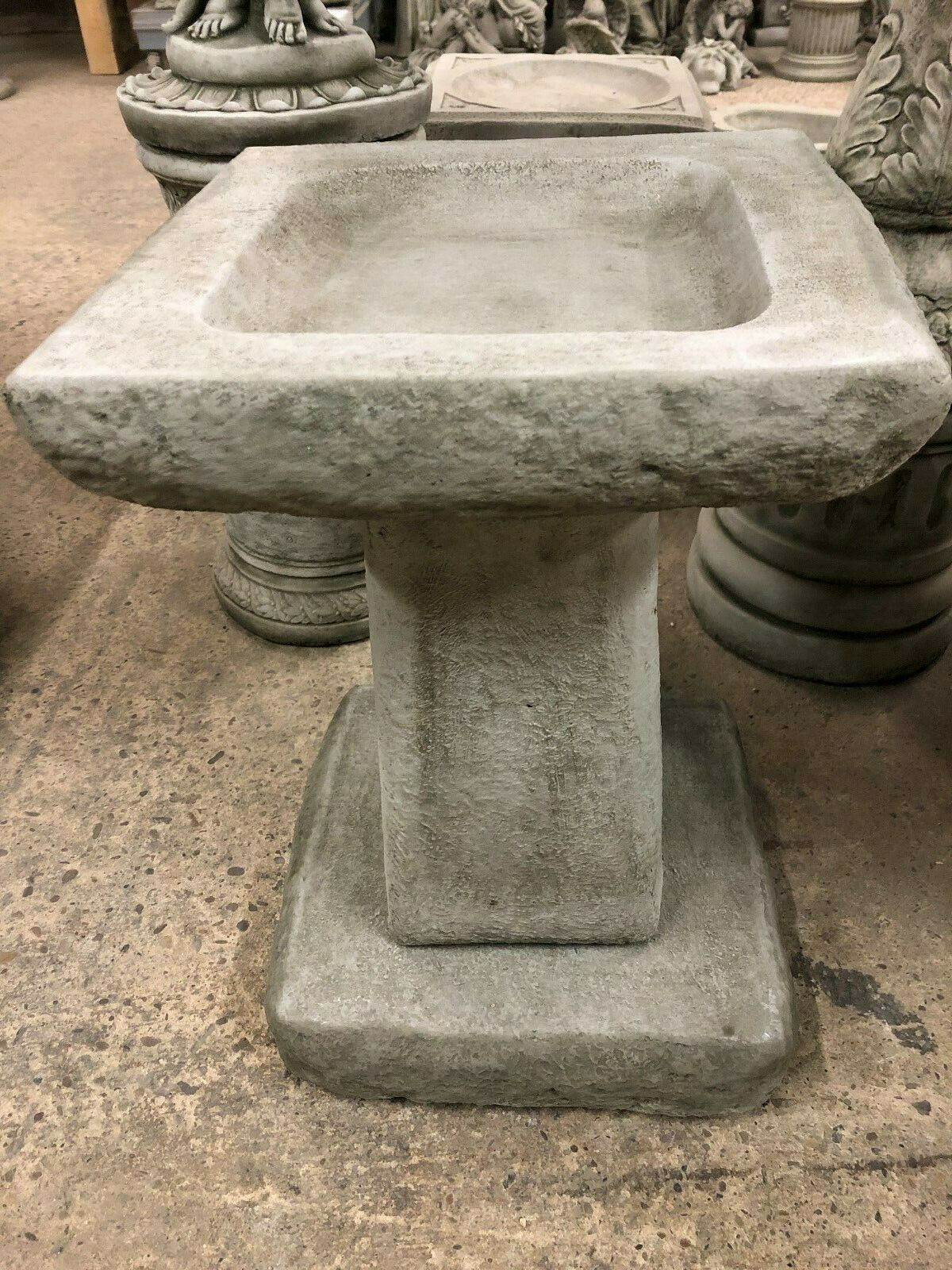 Chunky square stone garden bird bath crafted from durable limestone. Features a solid pedestal and textured antique finish for outdoor use.