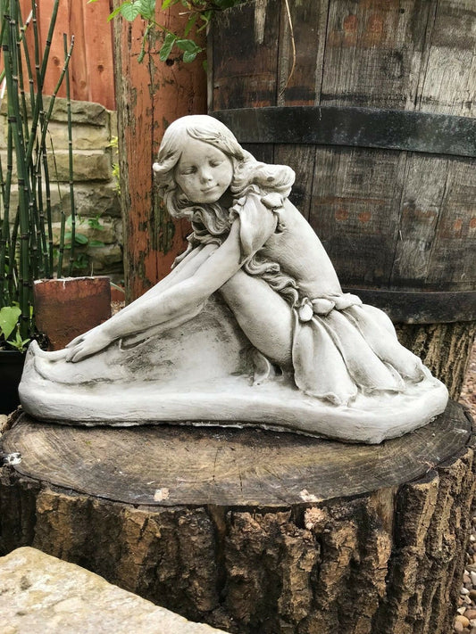 Stone Fairy Garden Ornament sculpture of a kneeling fairy girl with detailed dress, displayed on a tree stump in a rustic garden setting.