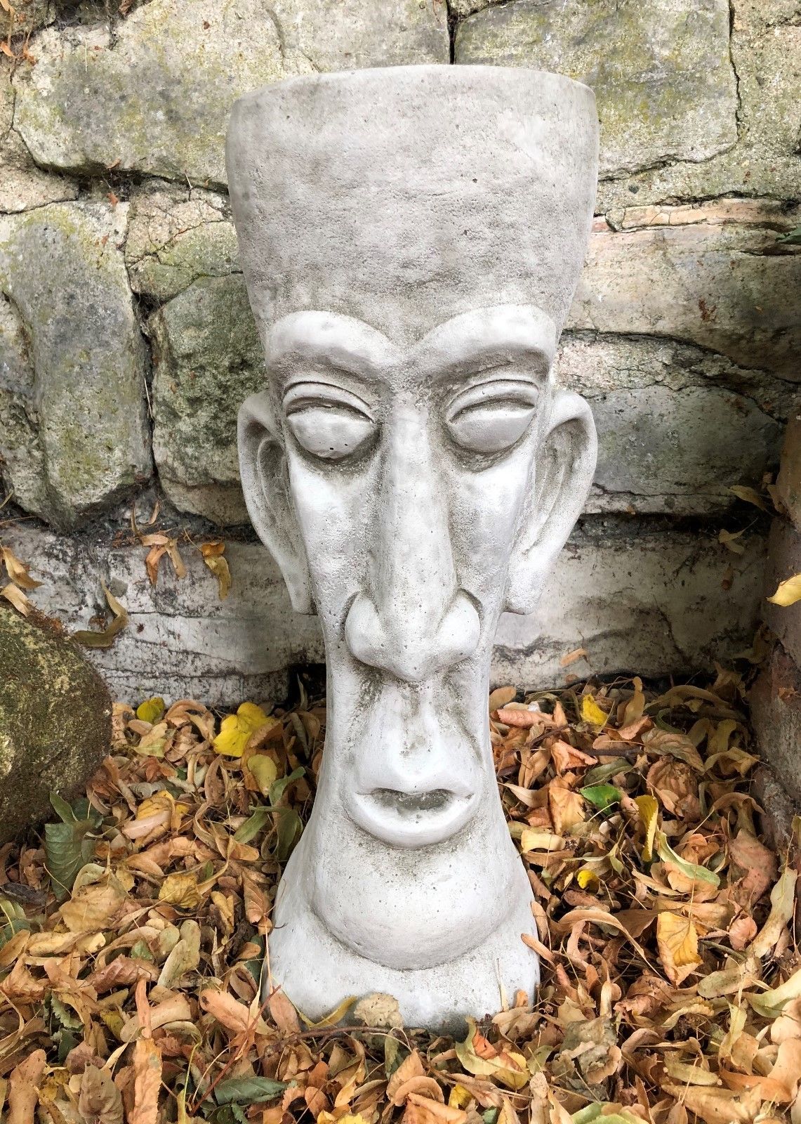 Front-facing Stone Easter Island Head Planter with deep-set eyes and elongated features, a striking garden decor piece for planting flowers.