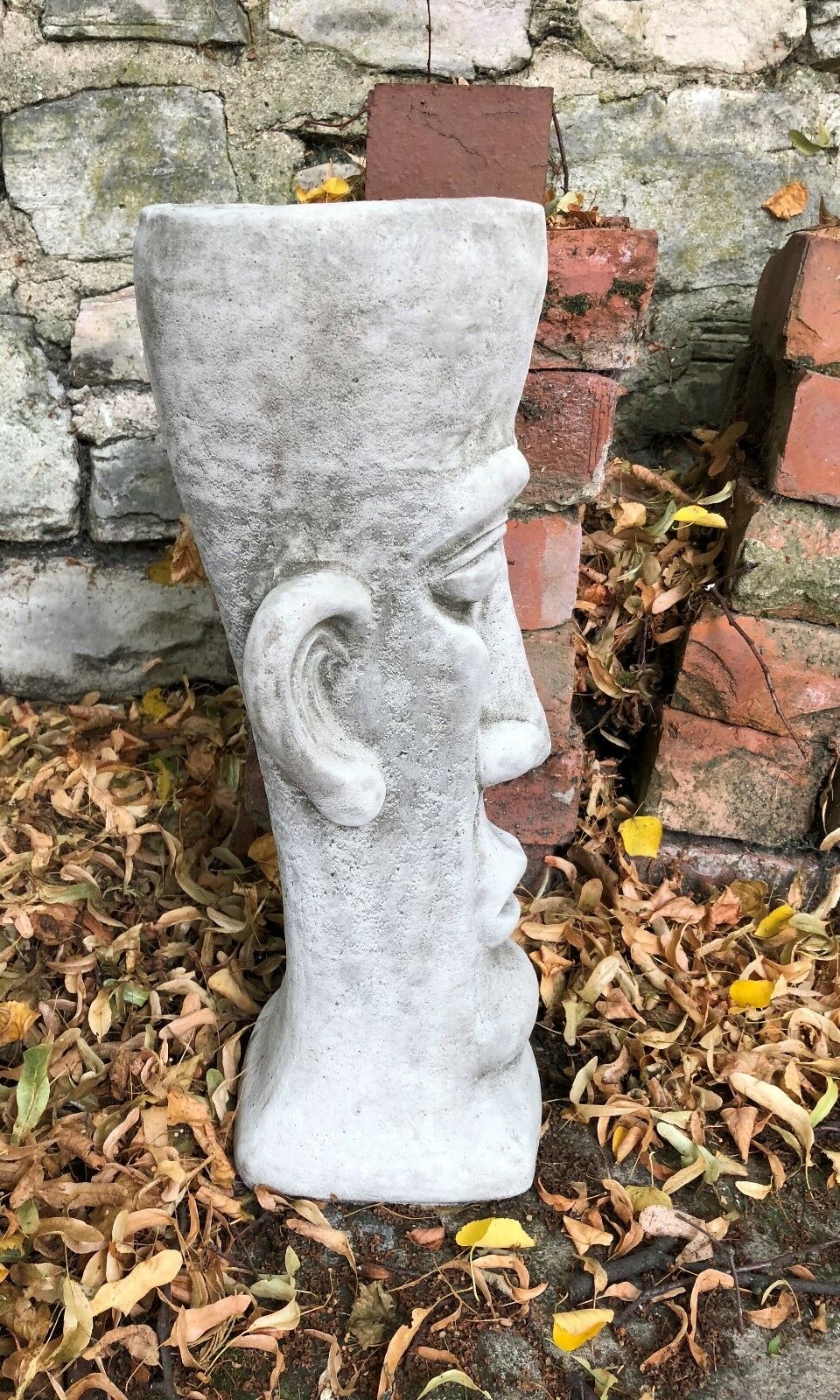 Profile view of the Stone Easter Island Head Planter showcasing its tall, narrow shape and weathered stone texture for outdoor use.