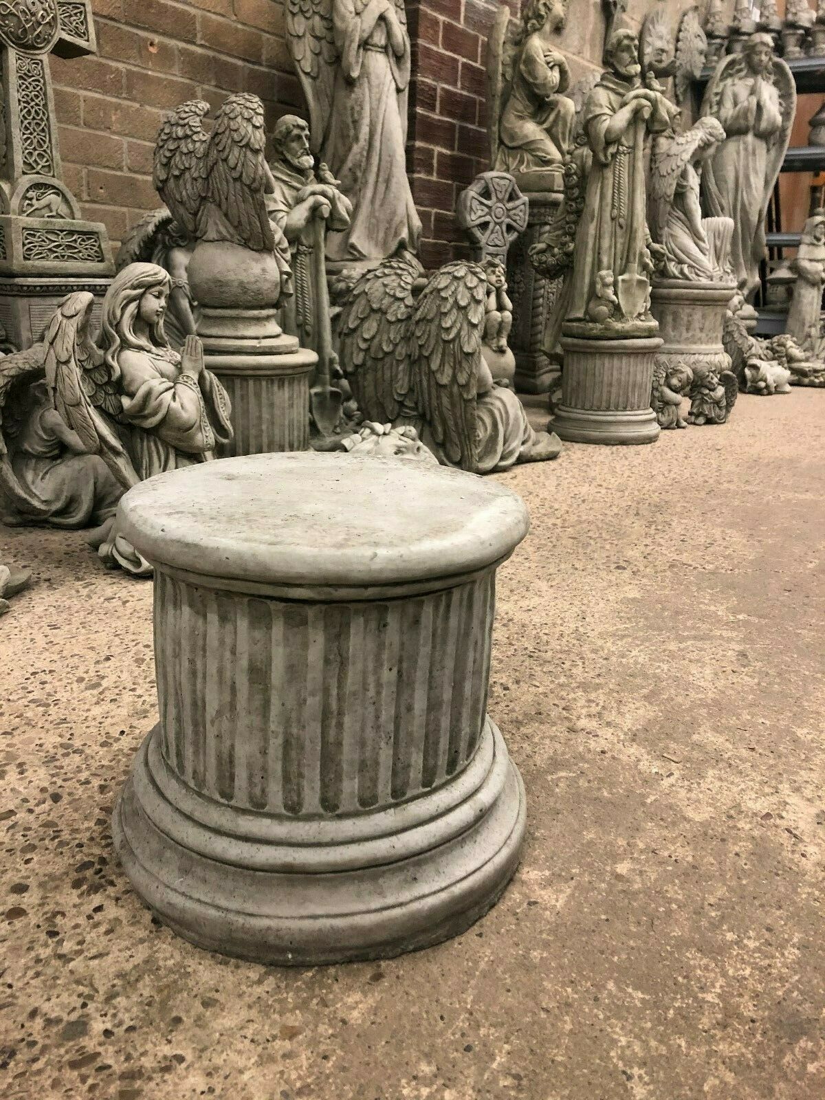 Stone column sculpture - small round plinth displayed among garden statues, perfect for enhancing patio or garden aesthetics.