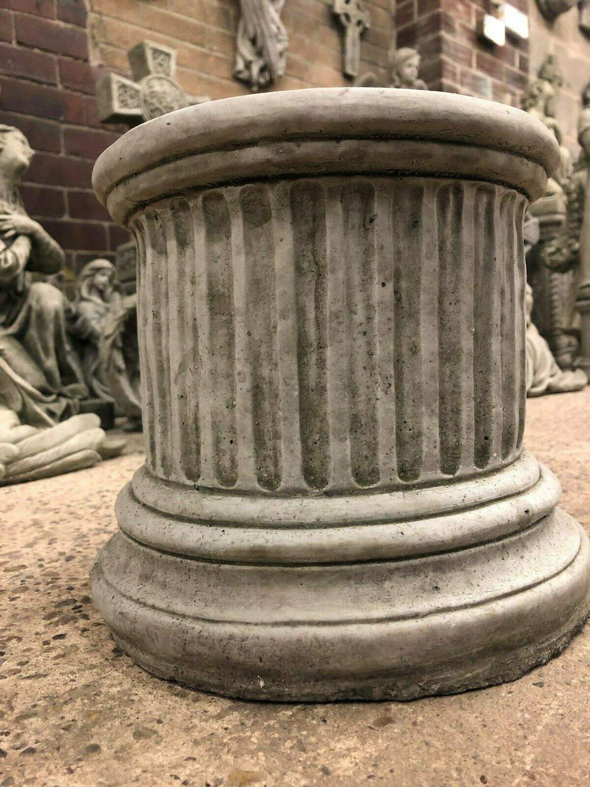 Close-up of small round stone column plinth showing detailed fluted limestone texture, suitable for decorative garden use.