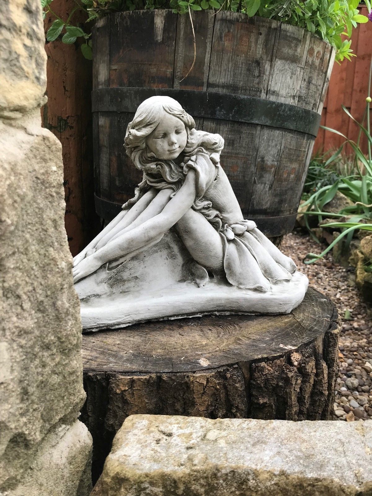 Close-up of a stone fairy garden ornament showing intricate facial features and flowing dress, ideal for decorative outdoor use.
