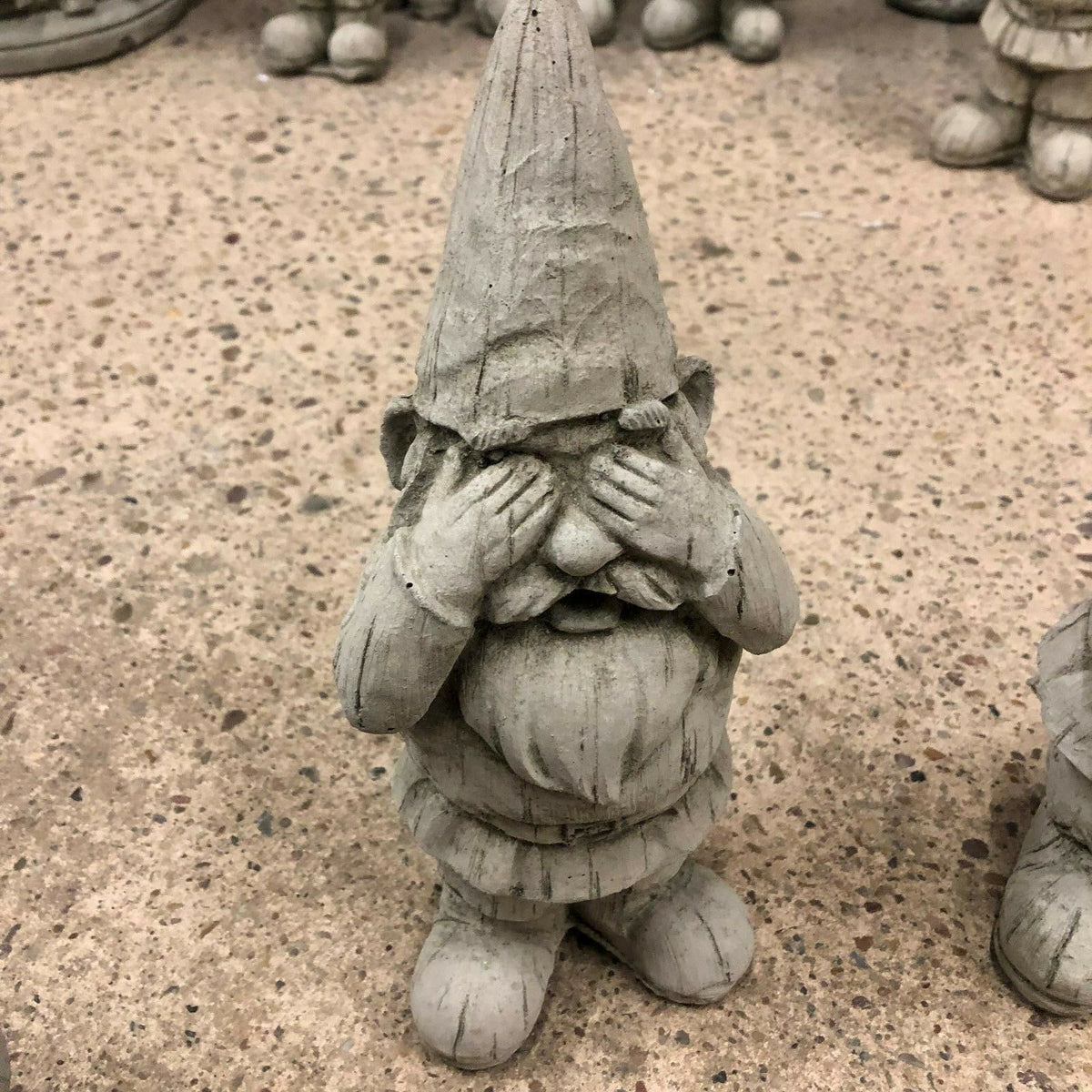 Close-up of 'See No Evil' gnome statue with hands over eyes. Stone finish adds rustic charm to garden or patio settings.