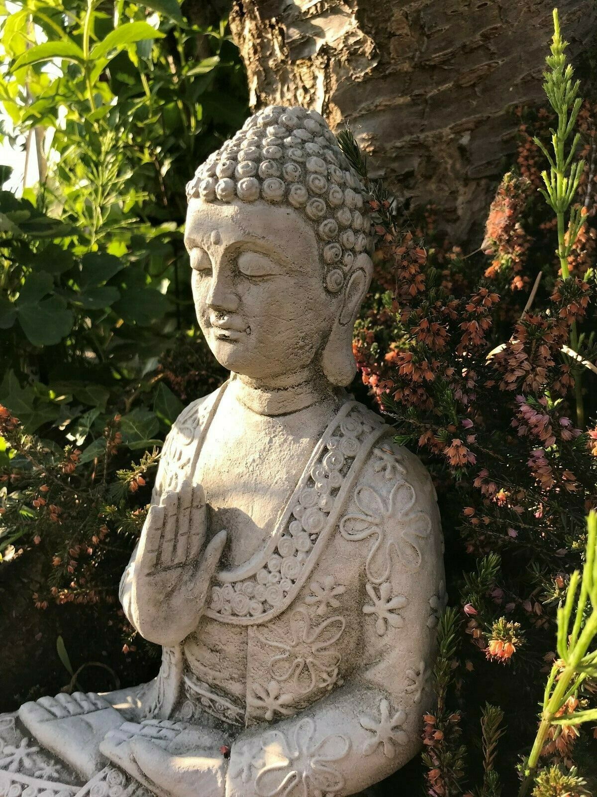 Angled view of Stone Buddha Garden Statue with antique grey finish and floral carvings, enhancing outdoor meditation areas.