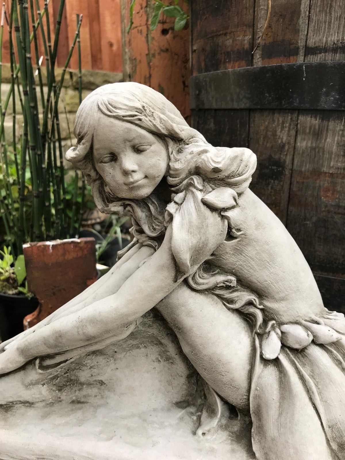 Detailed close-up of fairy girl's face and upper body in limestone sculpture, showcasing fine craftsmanship for garden ornamentation.