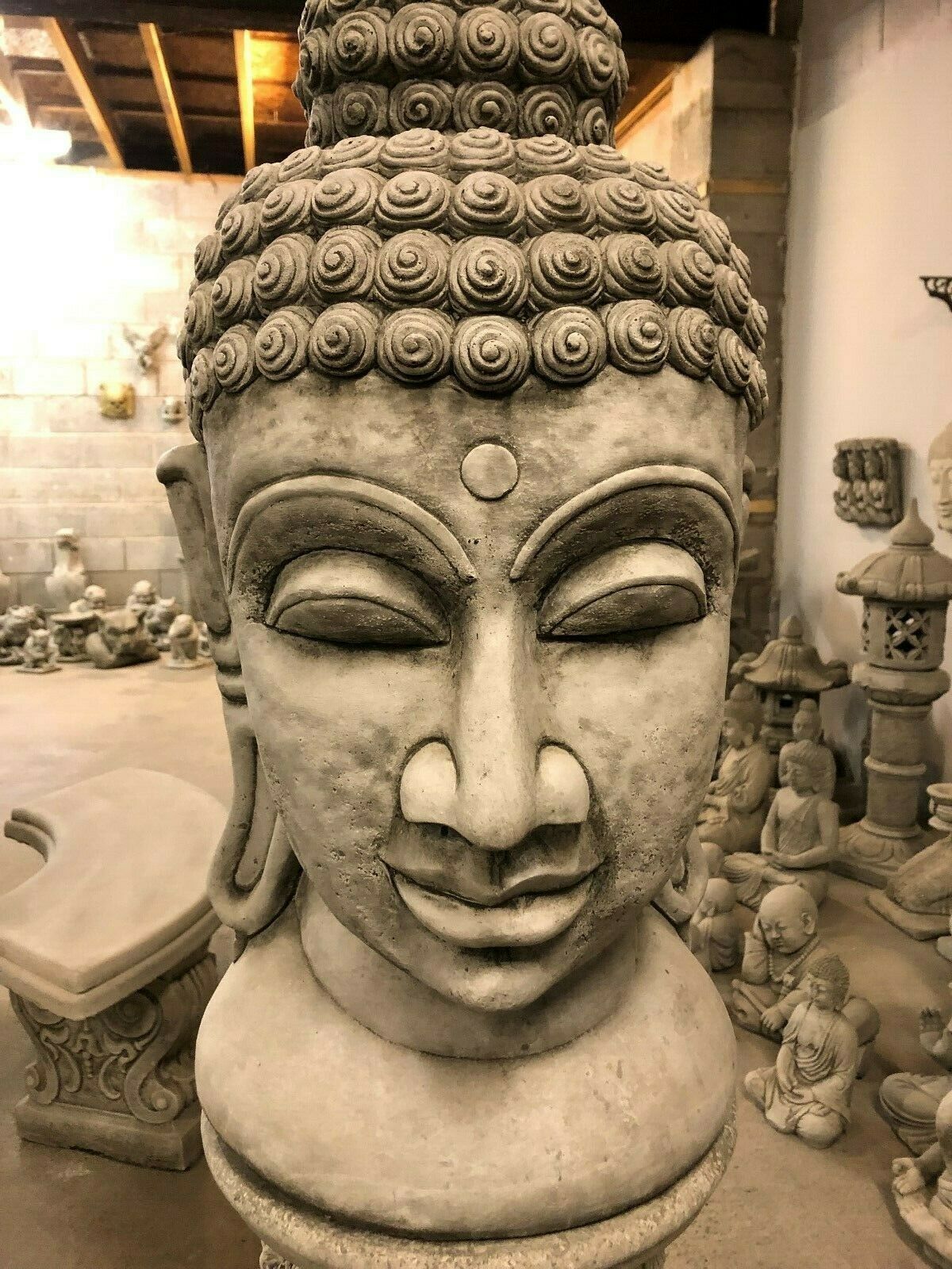 Front view of Buddha Head Garden Statue with serene expression. Weather-resistant limestone statue for peaceful garden ambiance.