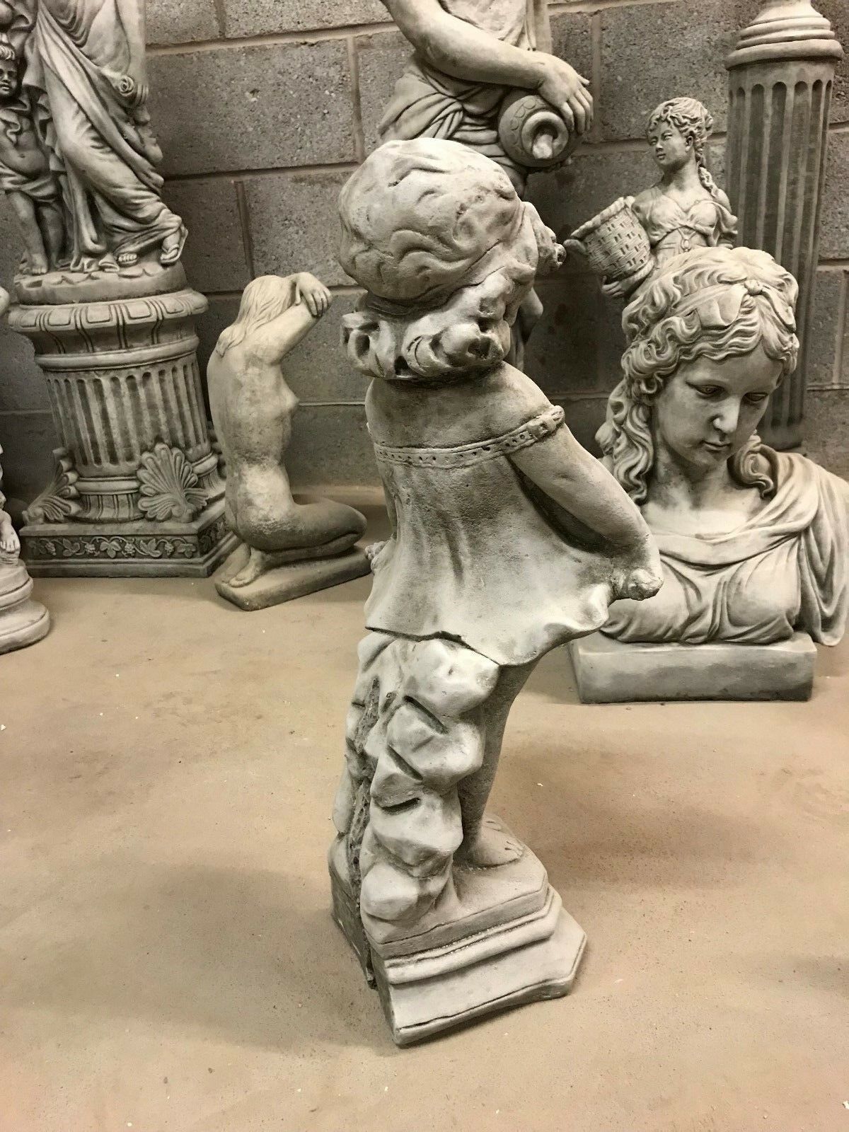 Rear side of Shy Girl Stone Sculpture showing textured stonework and support base, ideal for garden or patio display.