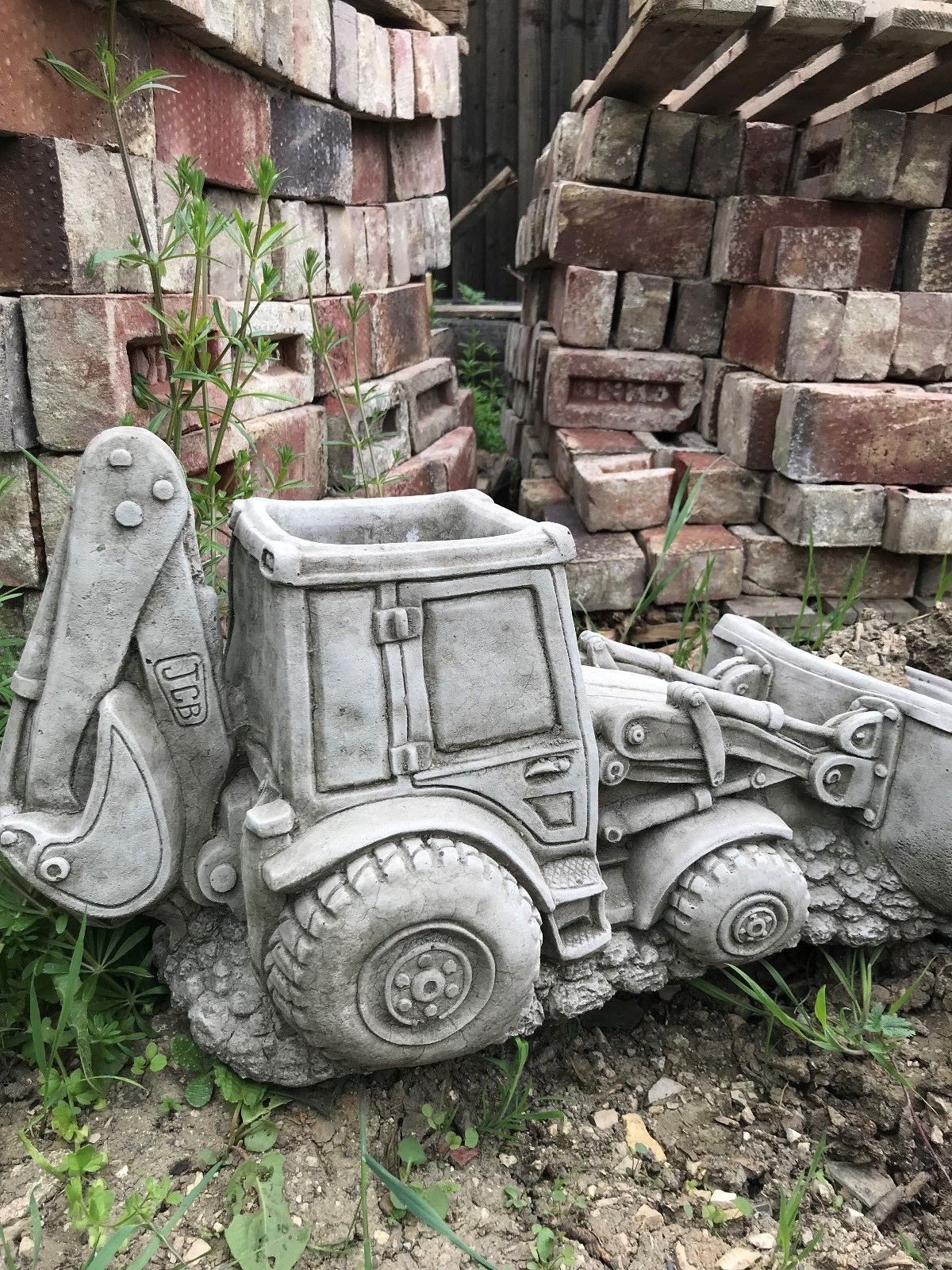 JCB Shovel Digger Planter - Garden Feature | Heavy & Durable decorative stone planter shaped like a JCB shovel loader, placed among garden bricks.