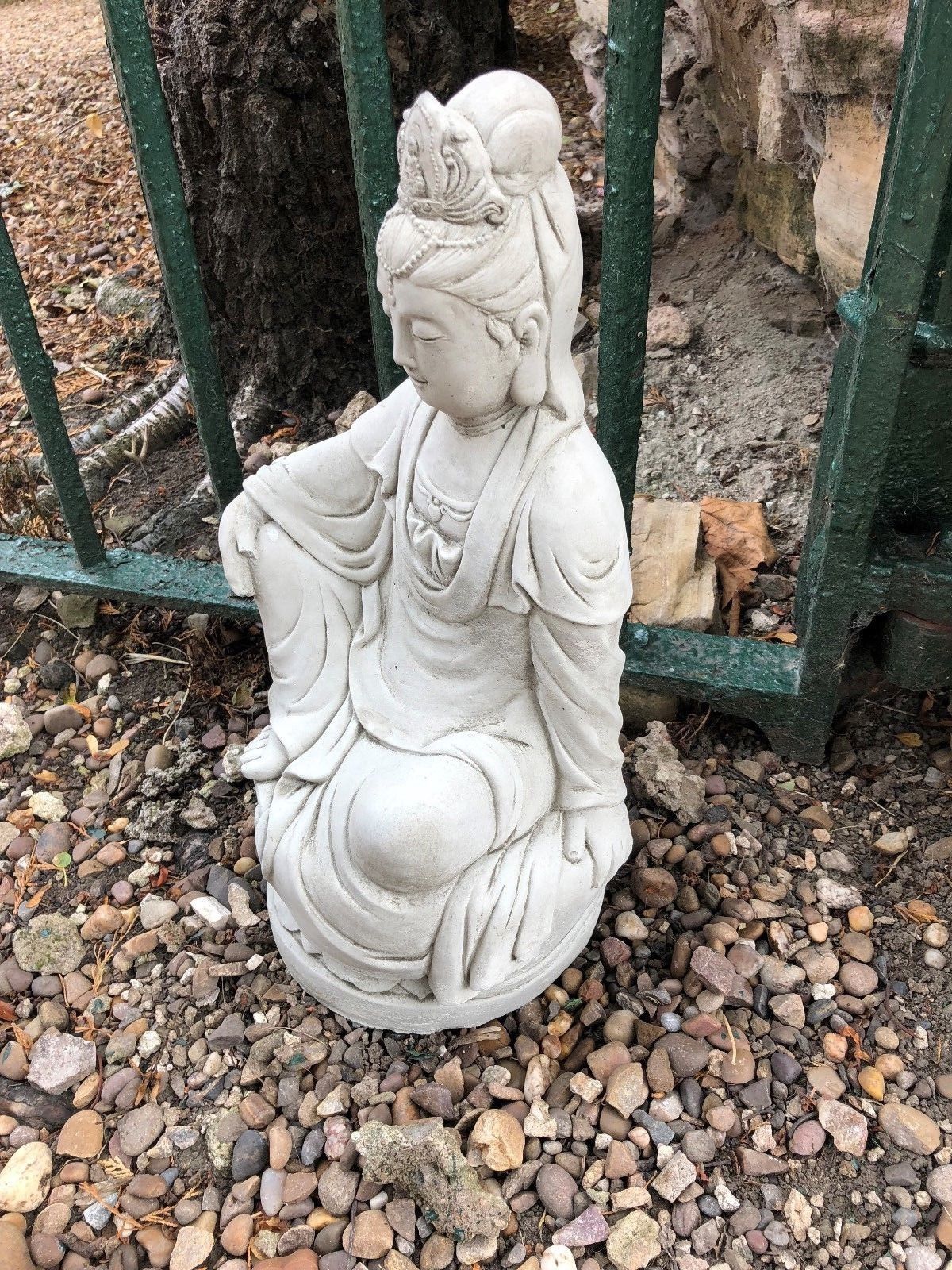 Top view of 18" Kuan Yin stone sculpture seated on lotus, placed on gravel. Durable garden ornament for spiritual outdoor ambiance.