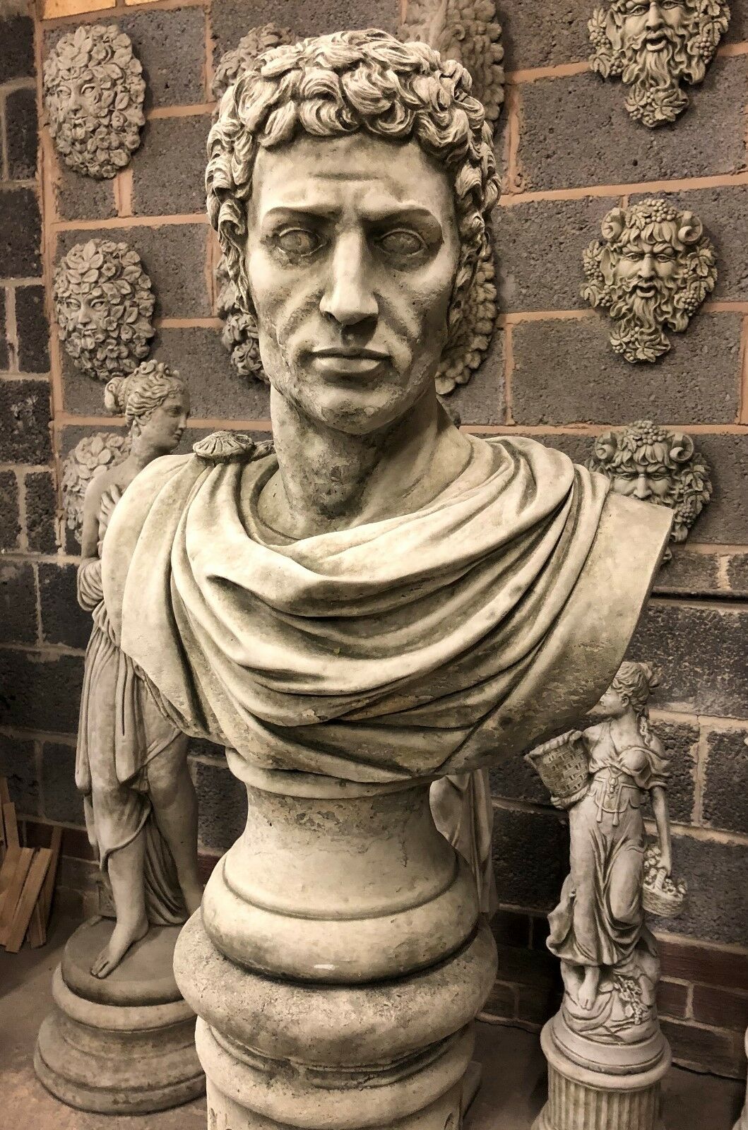 Stone Marc Anthony Bust Statue on Roman pillar pedestal, ideal for garden decor. Handcrafted limestone sculpture with detailed facial features.