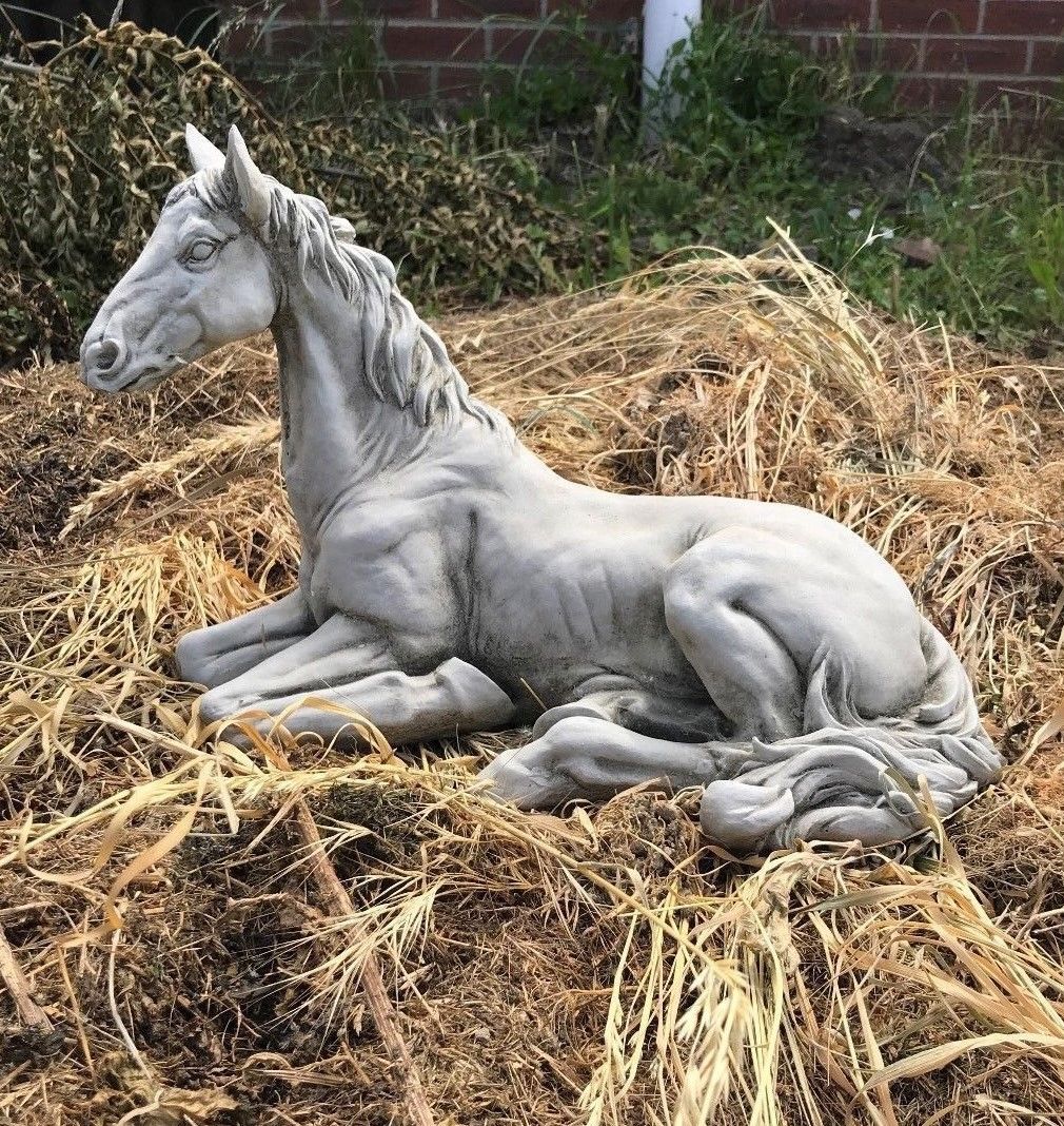 Stone Resting Horse Statue - Garden Ornament placed on dried grass, showcasing its elegant antique finish and realistic detailing.
