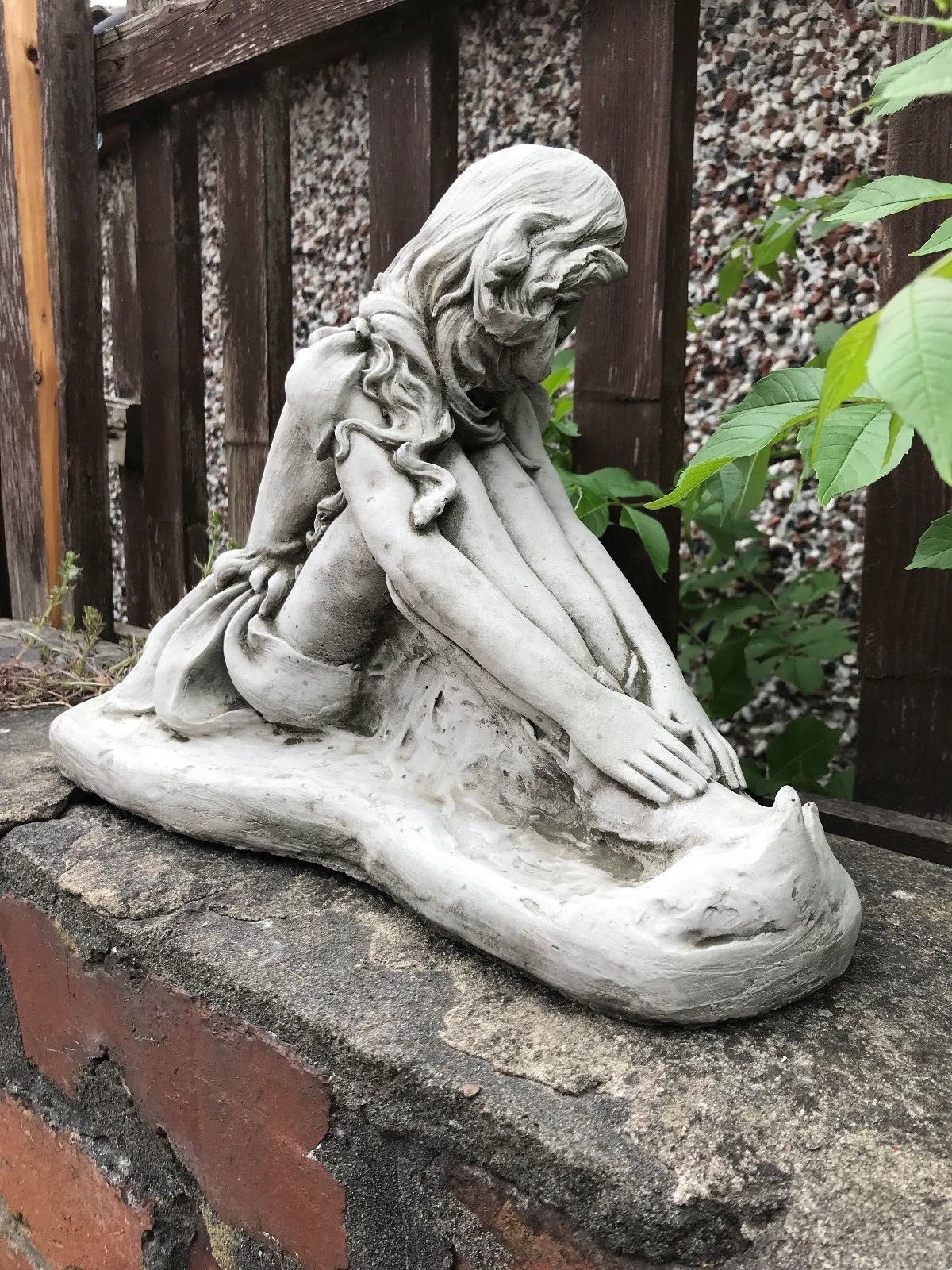 Side angle of fairy garden statue showing extended arms and textured base, made from weatherproof limestone for UK gardens.