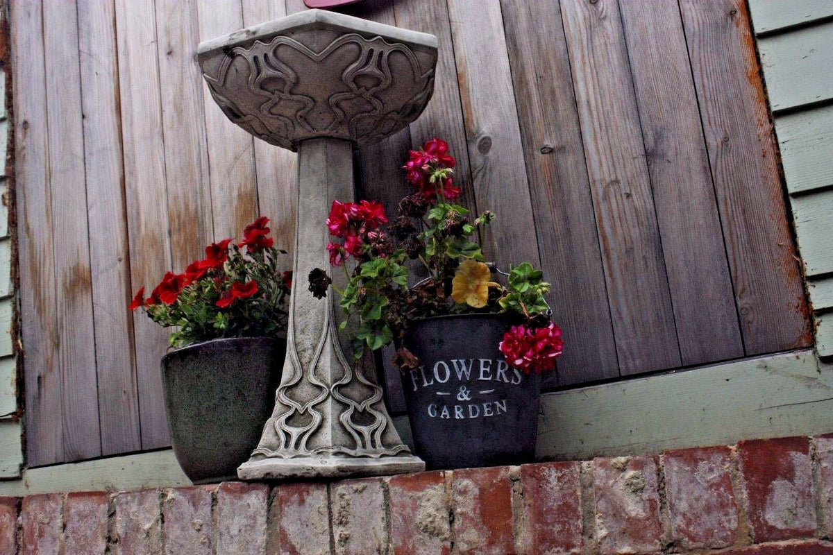 Art Nouveau Bird Bath with floral carvings placed beside flower pots on a brick ledge. Solid stone design for patios or garden corners.
