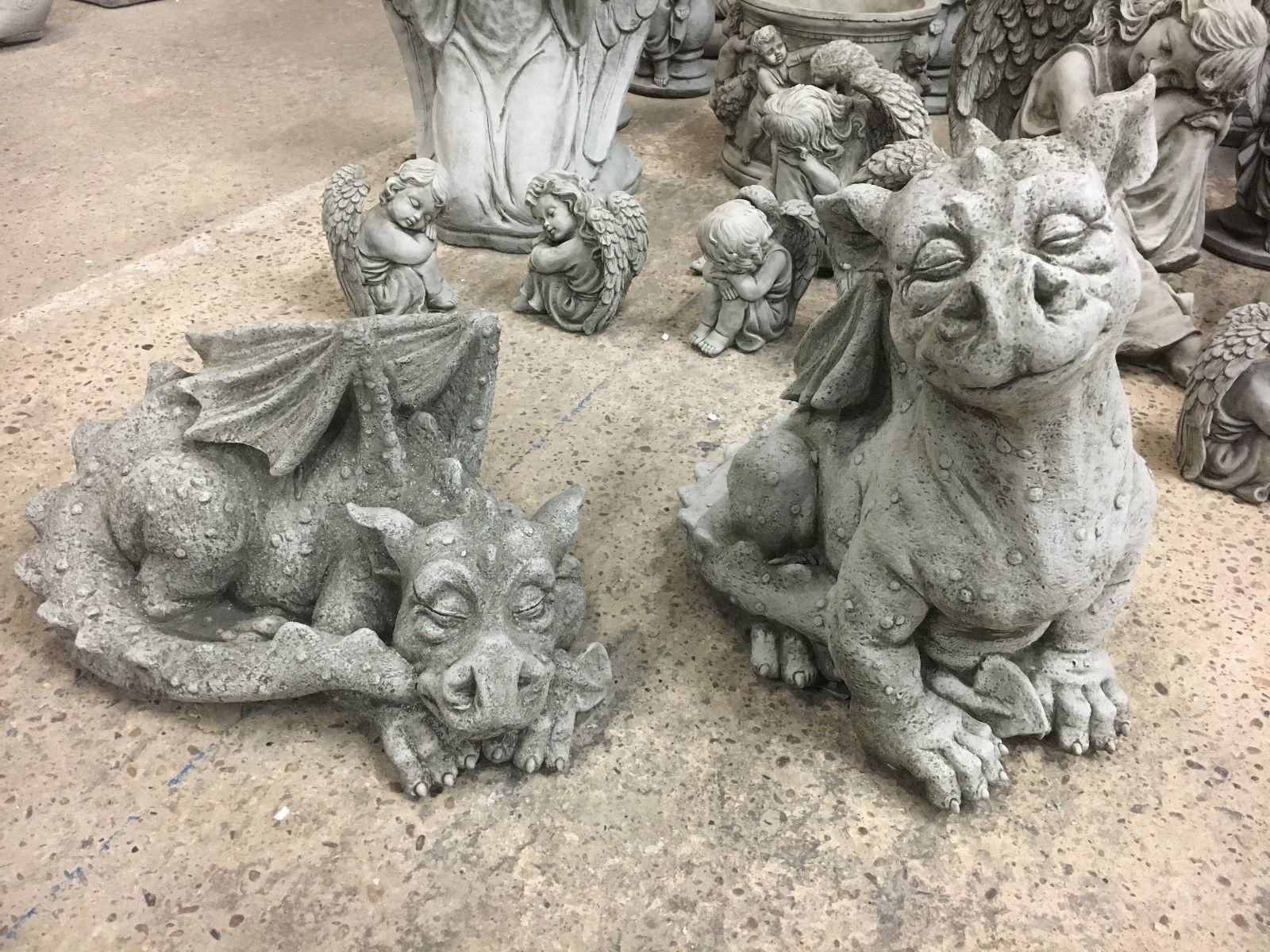 Pair of stone baby dragon garden statues with antique grey finish, featuring one sleeping and one sitting dragon. Ideal for outdoor lawn decor.
