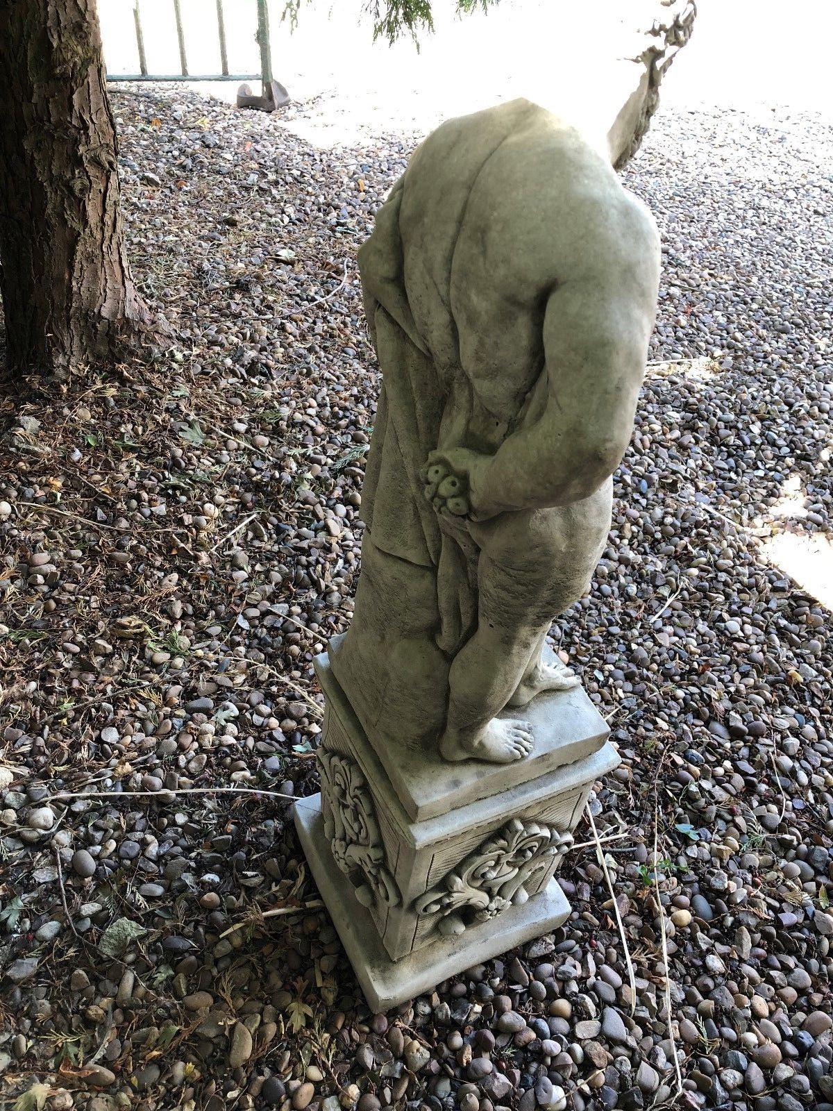 Rear view of Hercules garden statue revealing sculpted back and lion skin, mounted on a decorative limestone pedestal.