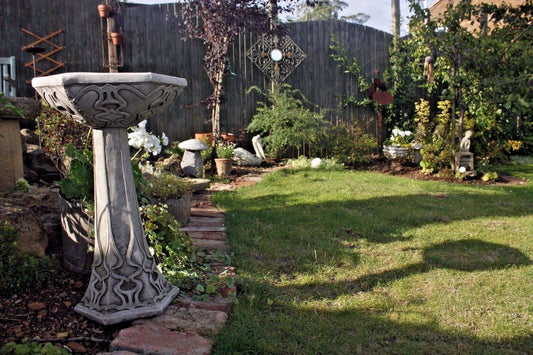 Freestanding Art Nouveau Garden Bird Bath in a landscaped backyard with stone base and ornate detailing. Ideal for outdoor garden decor.