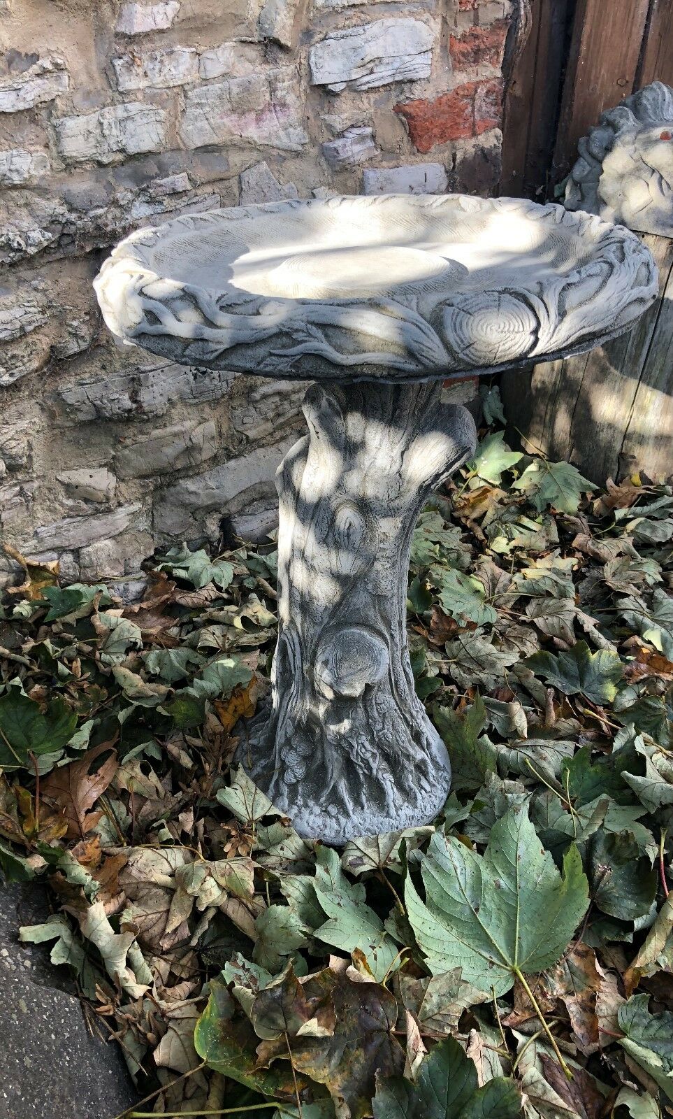 Handmade stone garden bird bath with intricate tree trunk design, ideal for bird feeding and garden ornamentation.