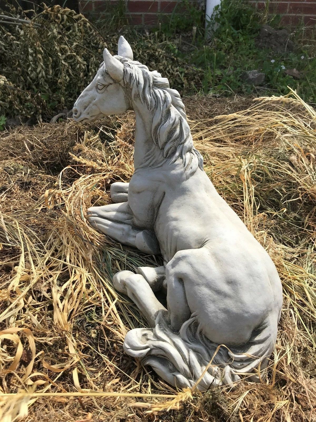 Angled side view of Stone Resting Horse Statue - Garden Ornament featuring elegant curves and lifelike posture for garden decor.