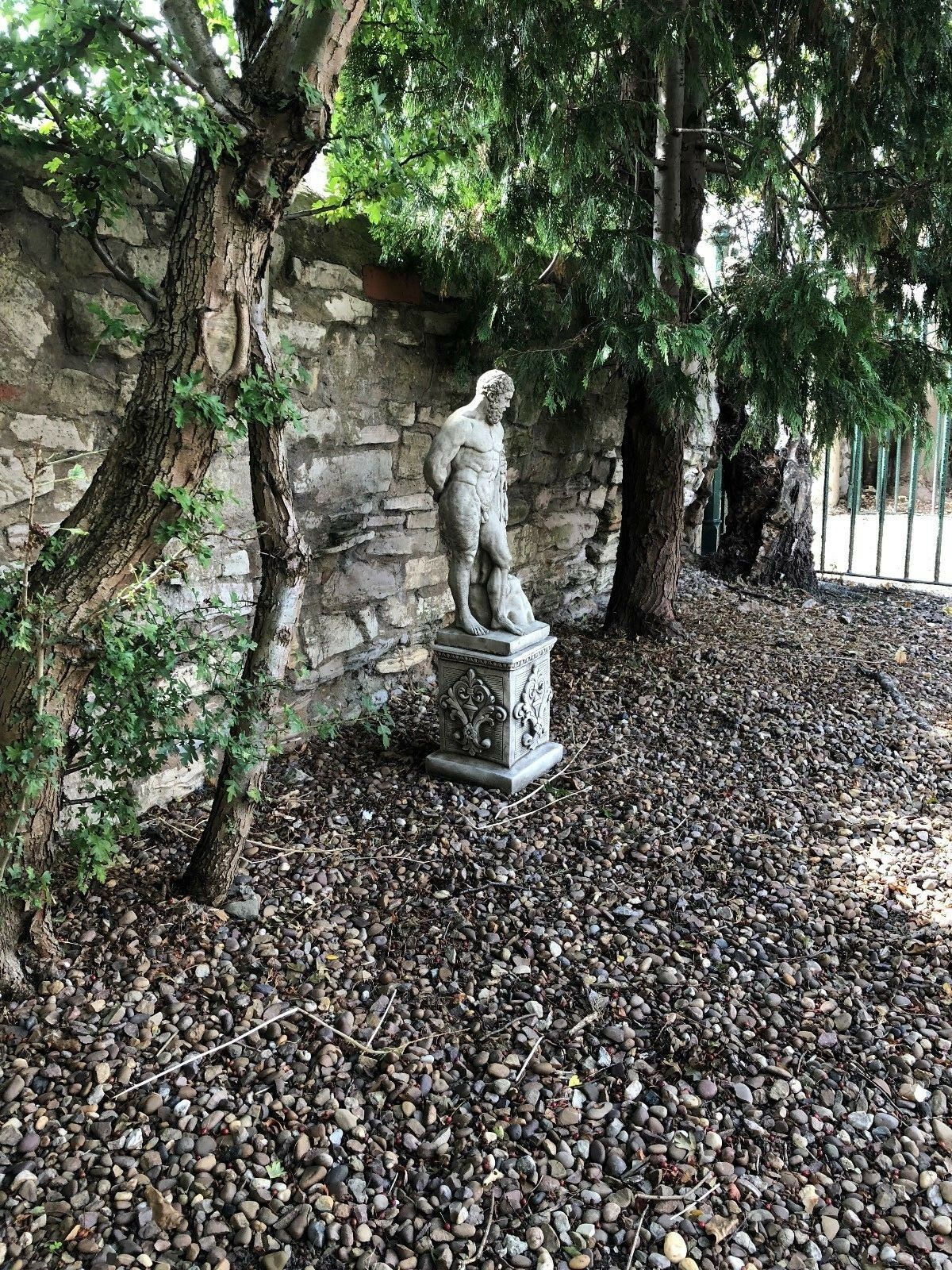 Hercules stone statue placed under trees in garden, enhancing outdoor space with mythological limestone sculpture.
