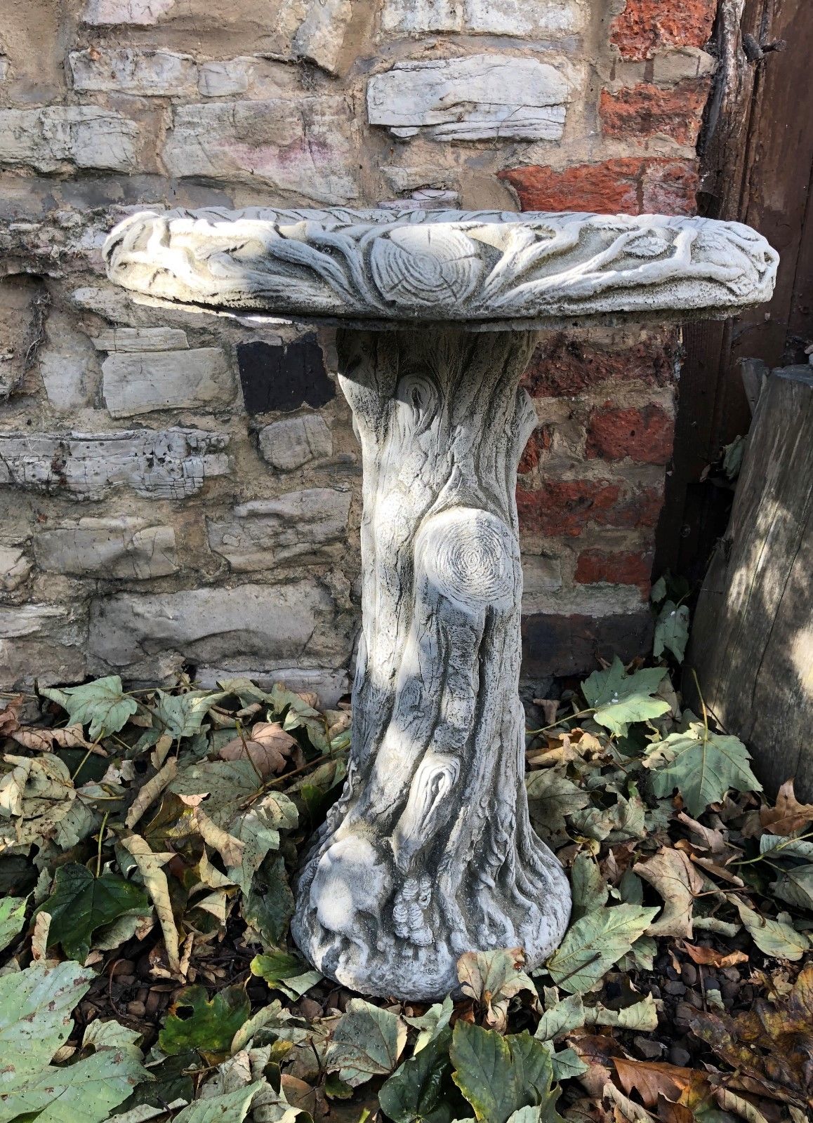 Round stone bird bath with tree stump-style base, perfect for UK gardens seeking a natural and decorative touch.