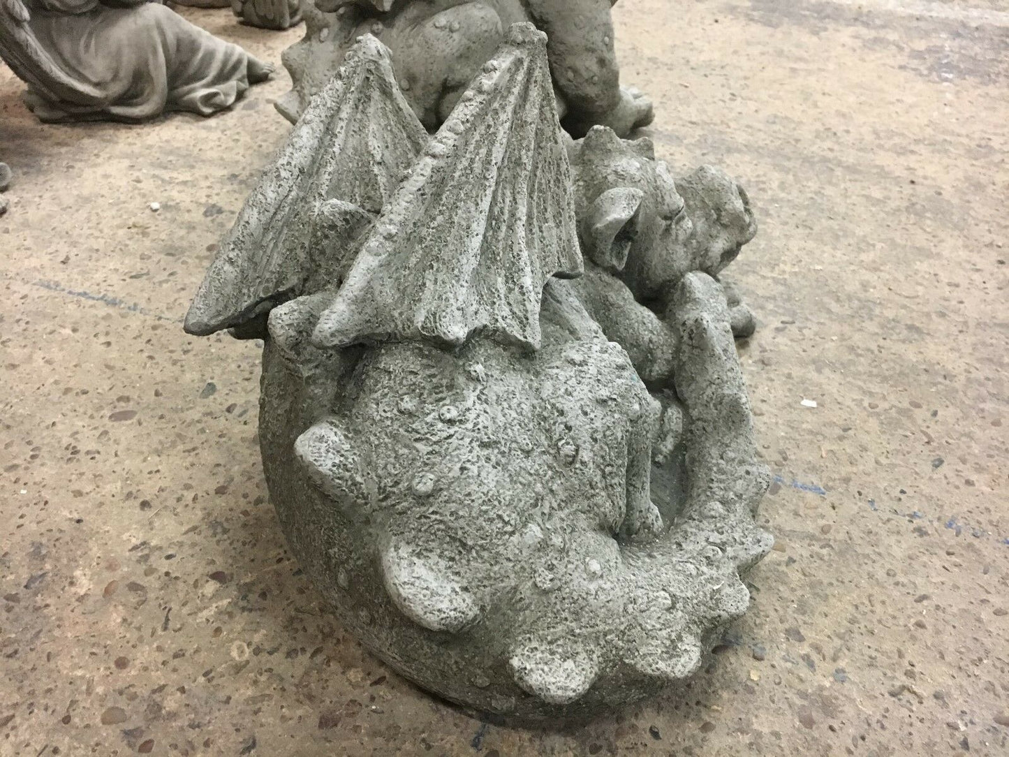 Side angle of curled stone baby dragon statue with antique finish, designed for outdoor garden sculpture collections.