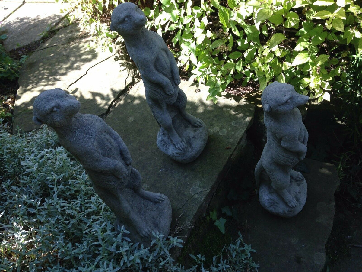 Top view of three stone meerkat statues arranged on a garden path, enhancing outdoor space with rustic charm.