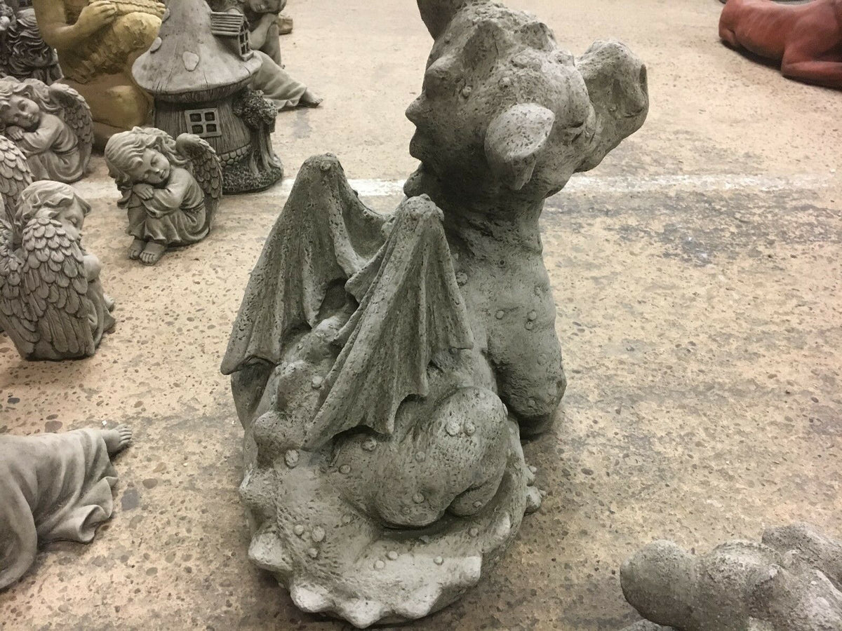 Back view of sitting baby dragon statue with wings folded, part of a decorative stone garden ornament set.