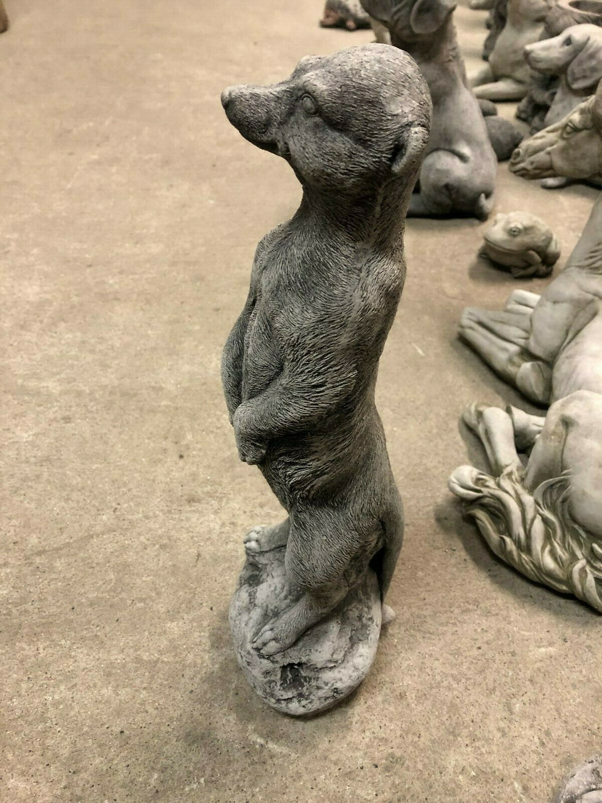 Side profile of a stone meerkat garden sculpture on a concrete floor, showcasing realistic detail for outdoor decor.
